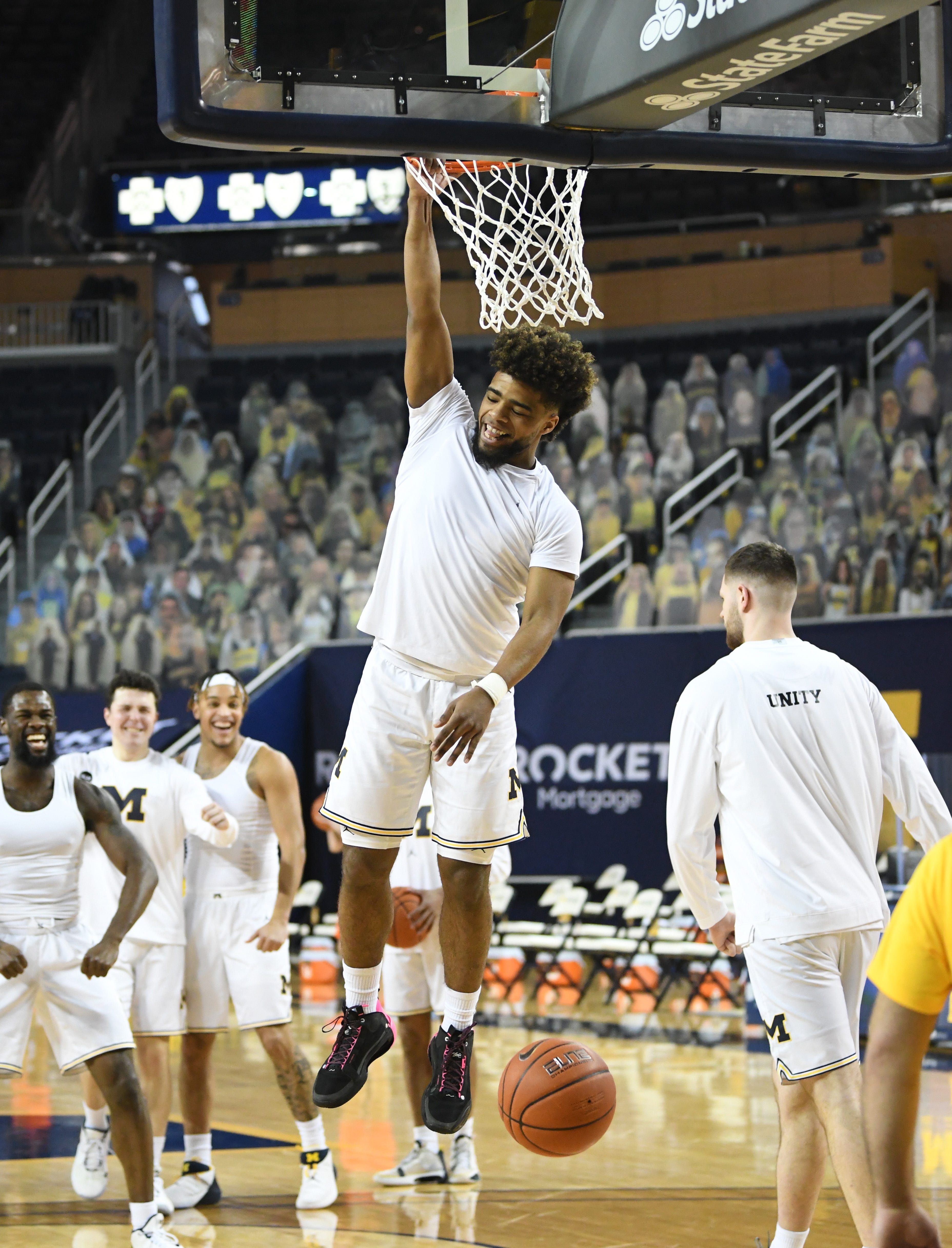Michigan's Mike Davis onto the rim for awhile after dunking, with some help from his teammates at the end of warmups.