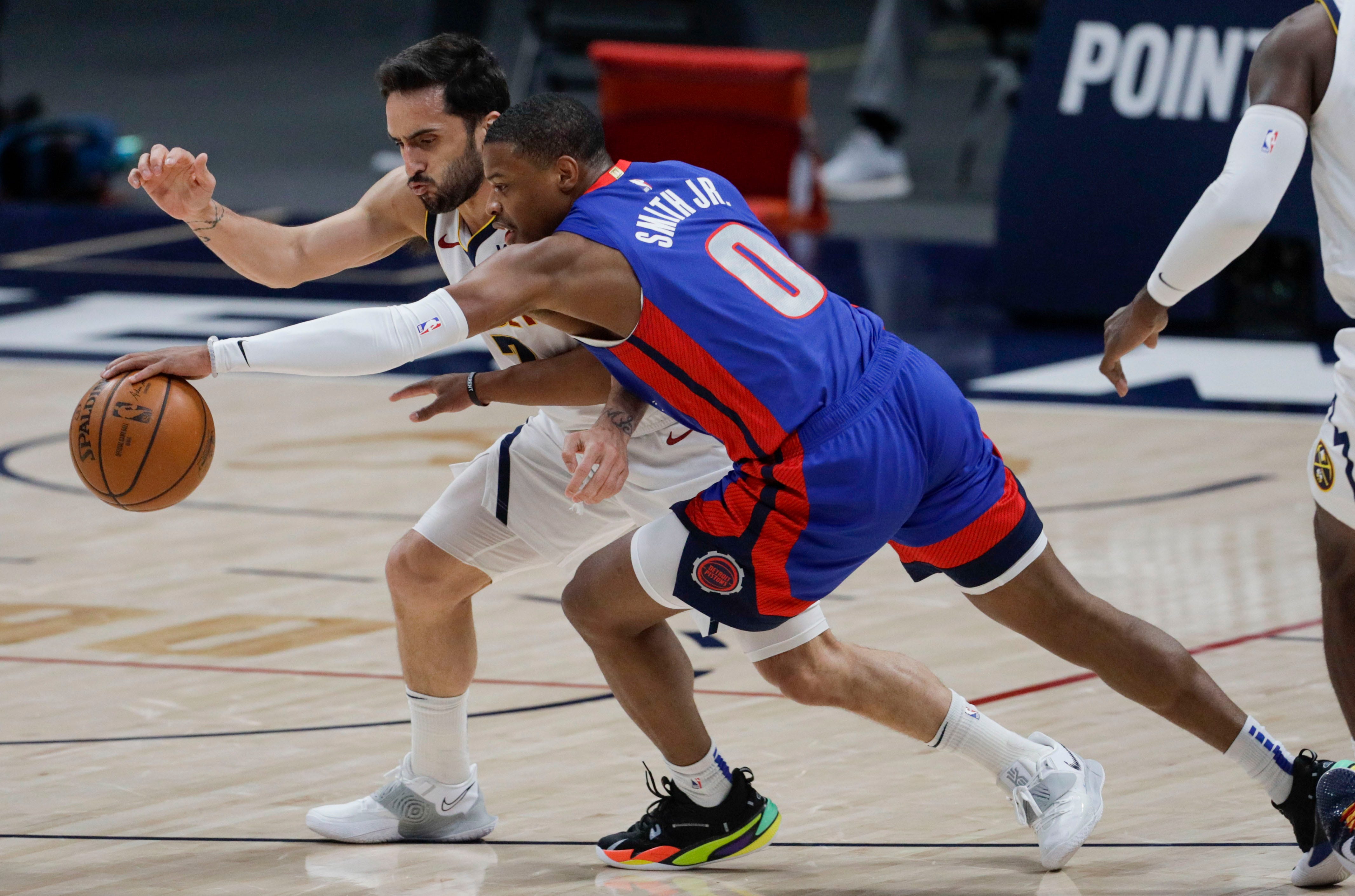 Detroit Pistons guard Dennis Smith Jr. (0) grabs a loose ball against Denver Nuggets guard Facundo Campazzo, right, in the first quarter of an NBA basketball game in Denver, Tuesday, April 6, 2021.