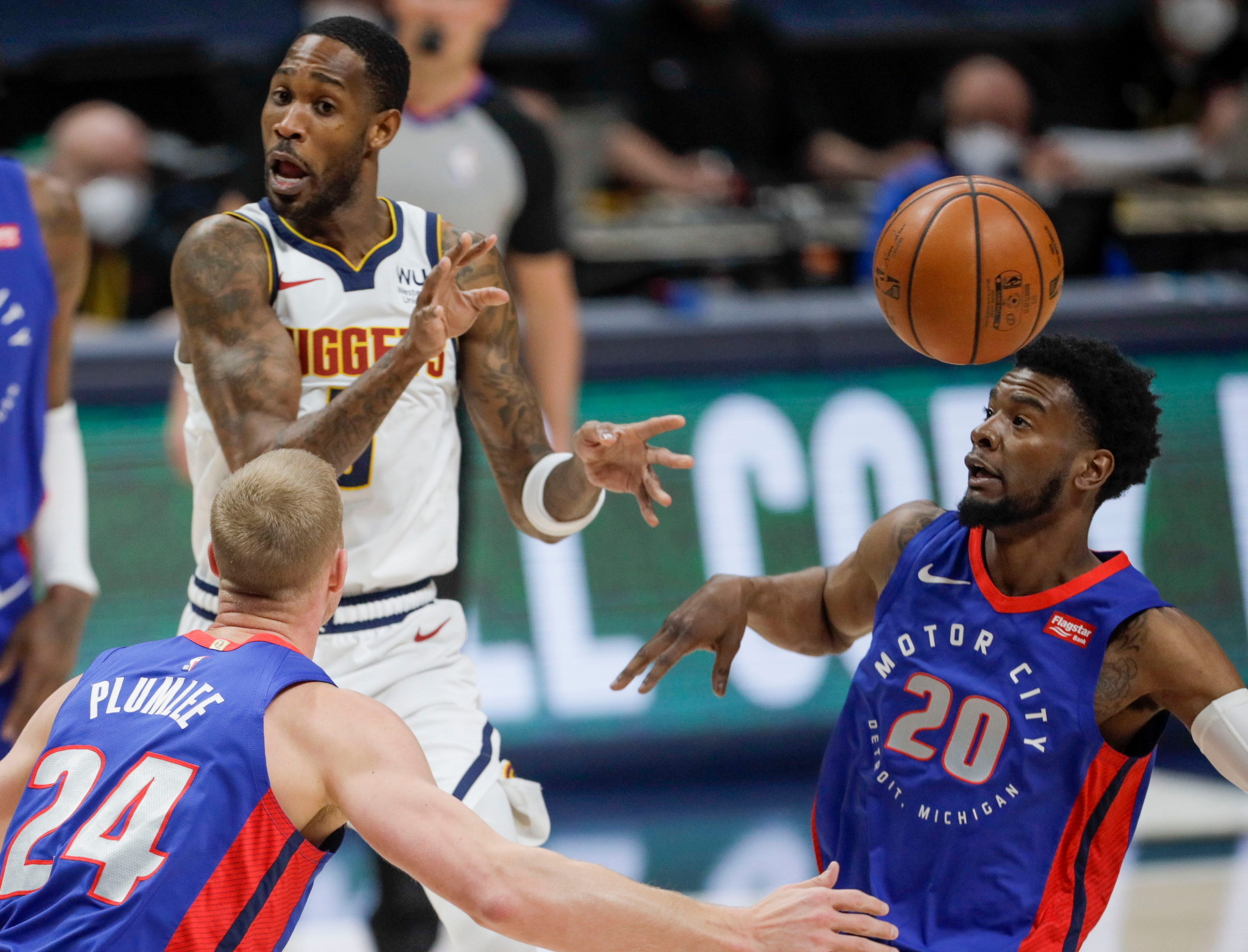 Denver Nuggets forward Will Barton, left, passes between Detroit Pistons center Mason Plumlee (24) and guard Josh Jackson (20) in the first quarter of an NBA basketball game in Denver, Tuesday, April 6, 2021.