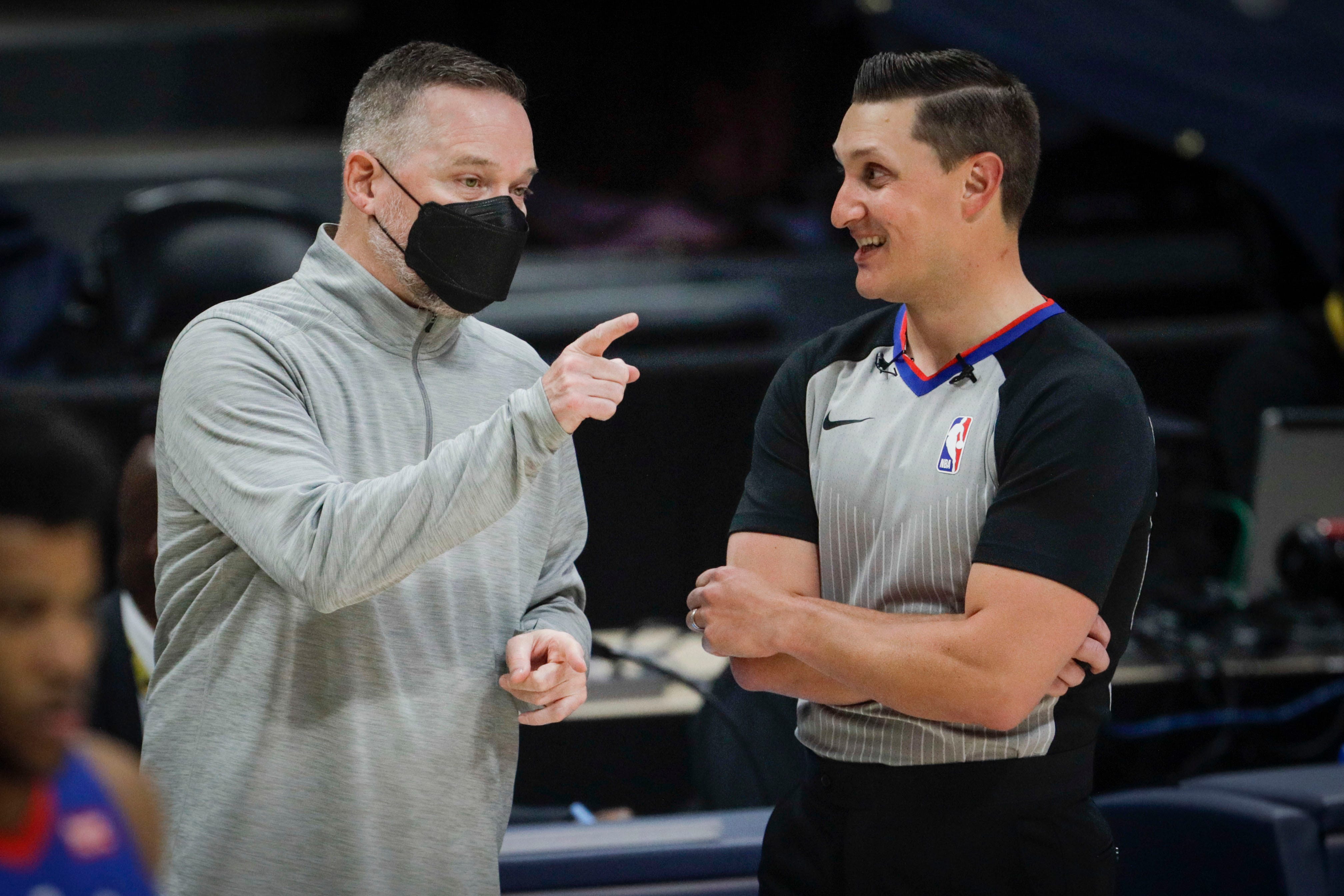 Denver Nuggets coach Michael Malone, left, talks to referee JB DeRosa (62) during a timeout in the third quarter of an NBA basketball game against the Detroit Pistons in Denver, Tuesday, April 6, 2021.