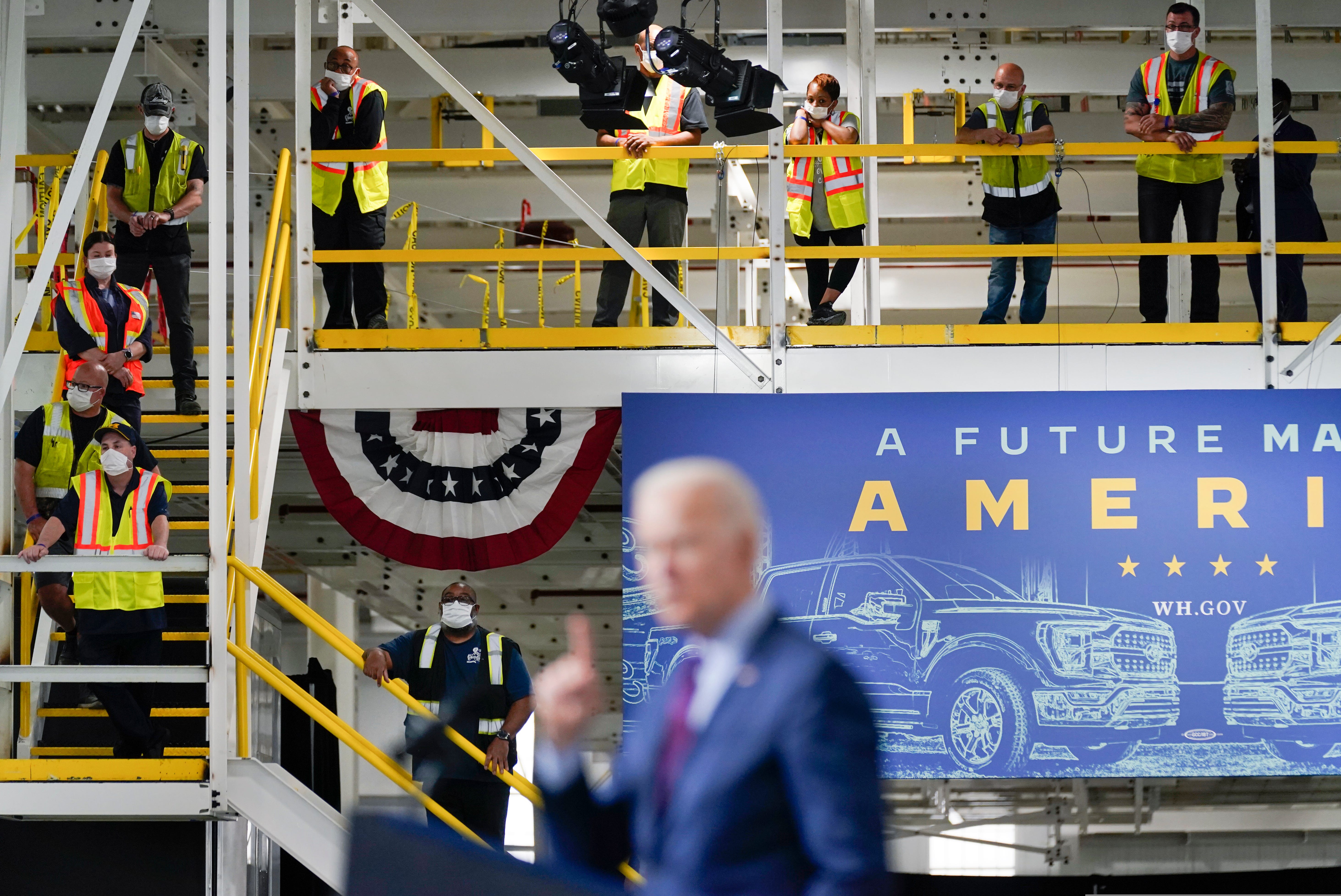 Workers listen as President Joe Biden speaks after a tour of the Ford Rouge EV Center, Tuesday, May 18, 2021, in Dearborn, Mich.