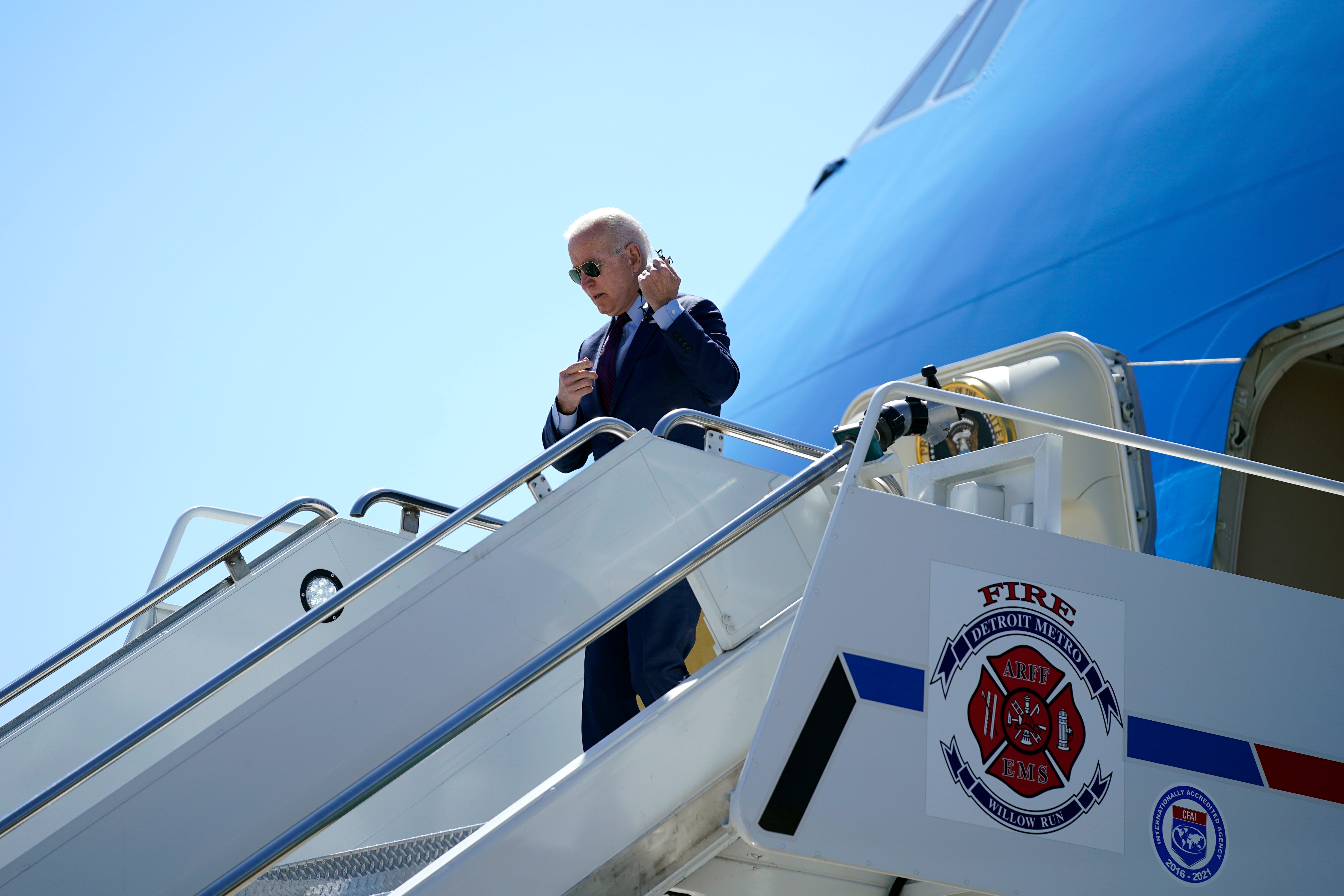 President Joe Biden removes his face mask as he arrives at Detroit Metropolitan Wayne County Airport in Detroit, Tuesday, May 18, 2021.
