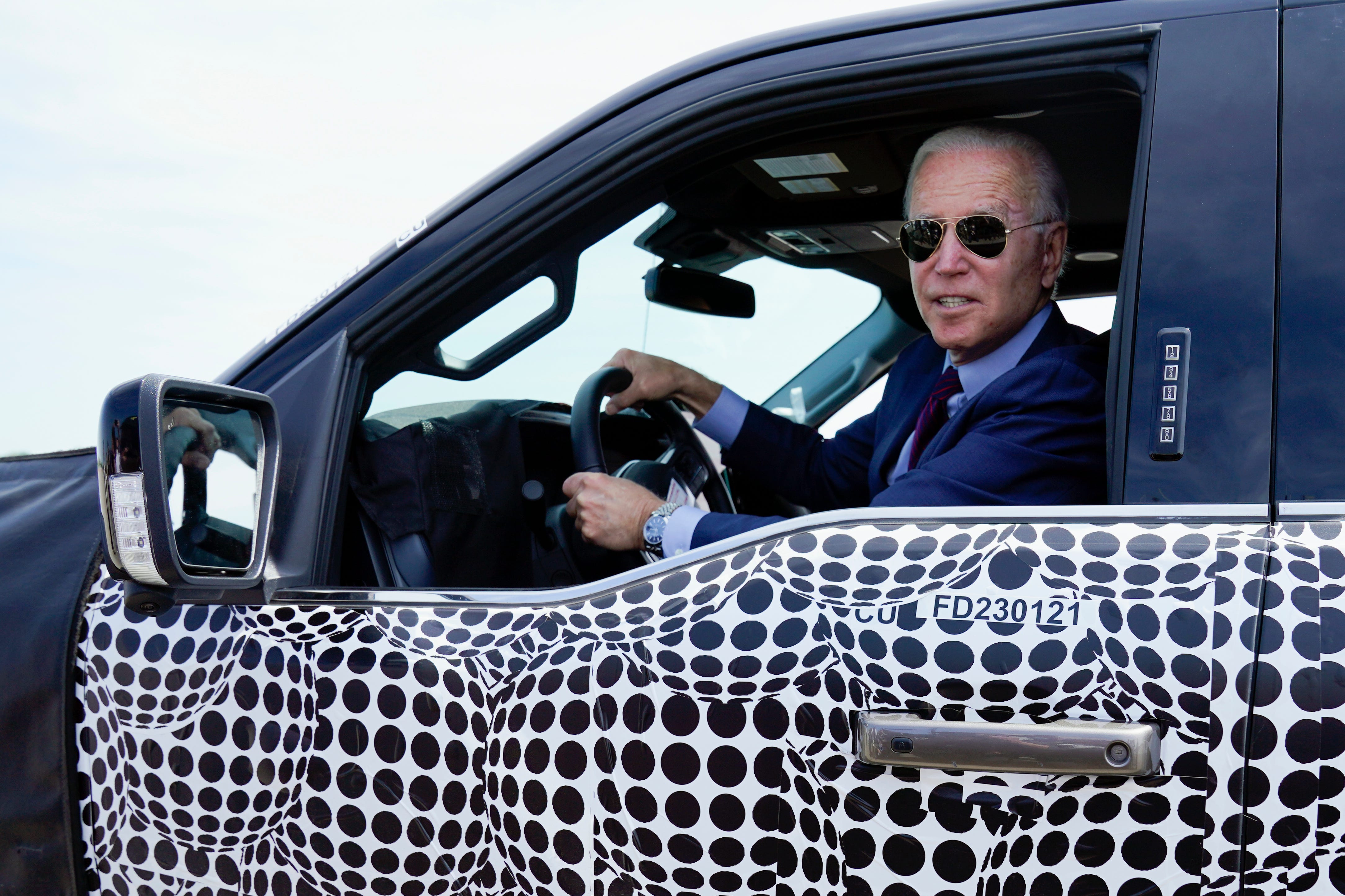 President Joe Biden stops to talk to the media as he drives a Ford F-150 Lightning truck at Ford Dearborn Development Center, Tuesday, May 18, 2021, in Dearborn.