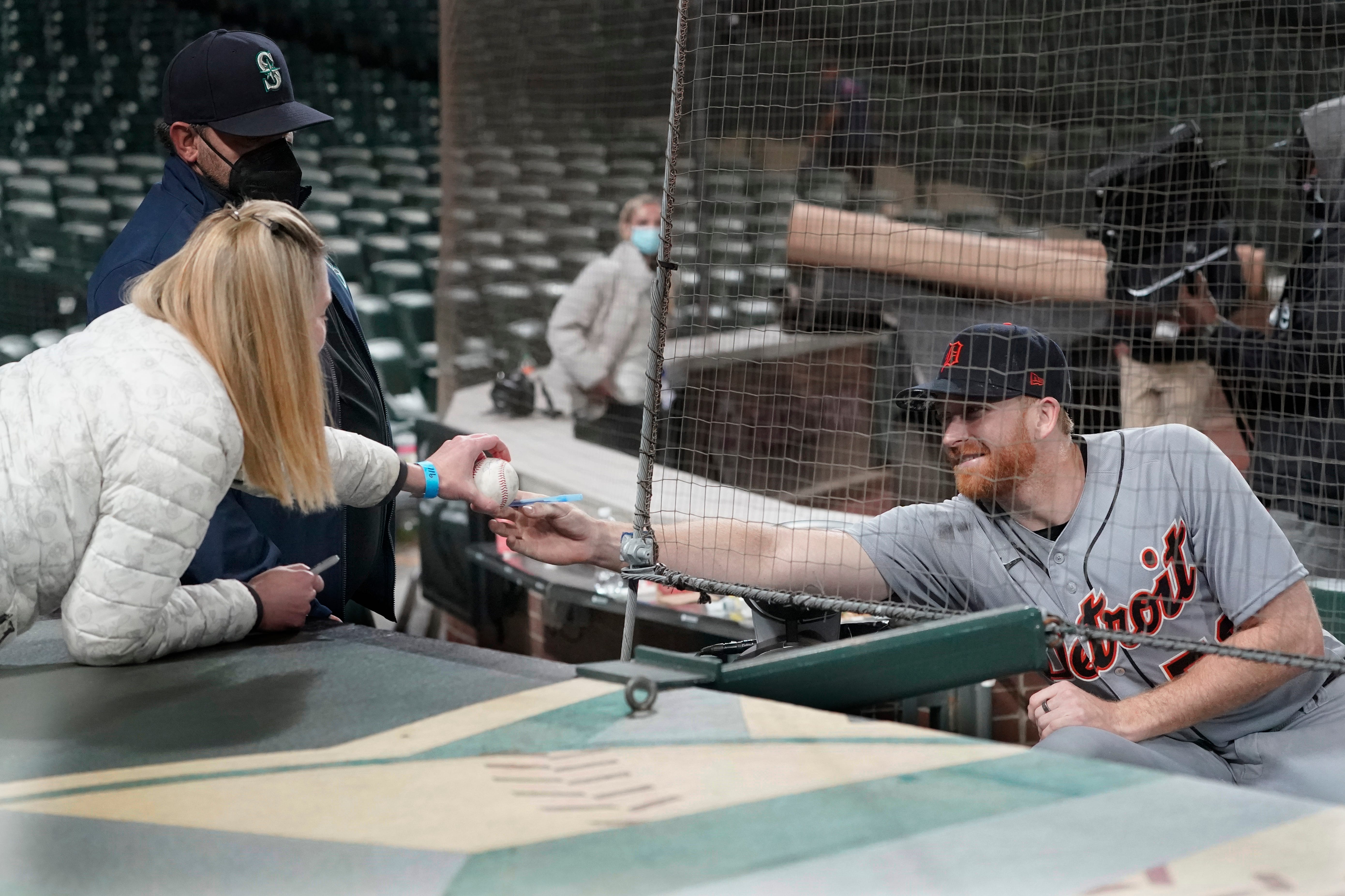Detroit Tigers starting pitcher Spencer Turnbull, right, signs a baseball for a fan after he threw a no-hitter baseball game against the Seattle Mariners, Tuesday, May 18, 2021, in Seattle.