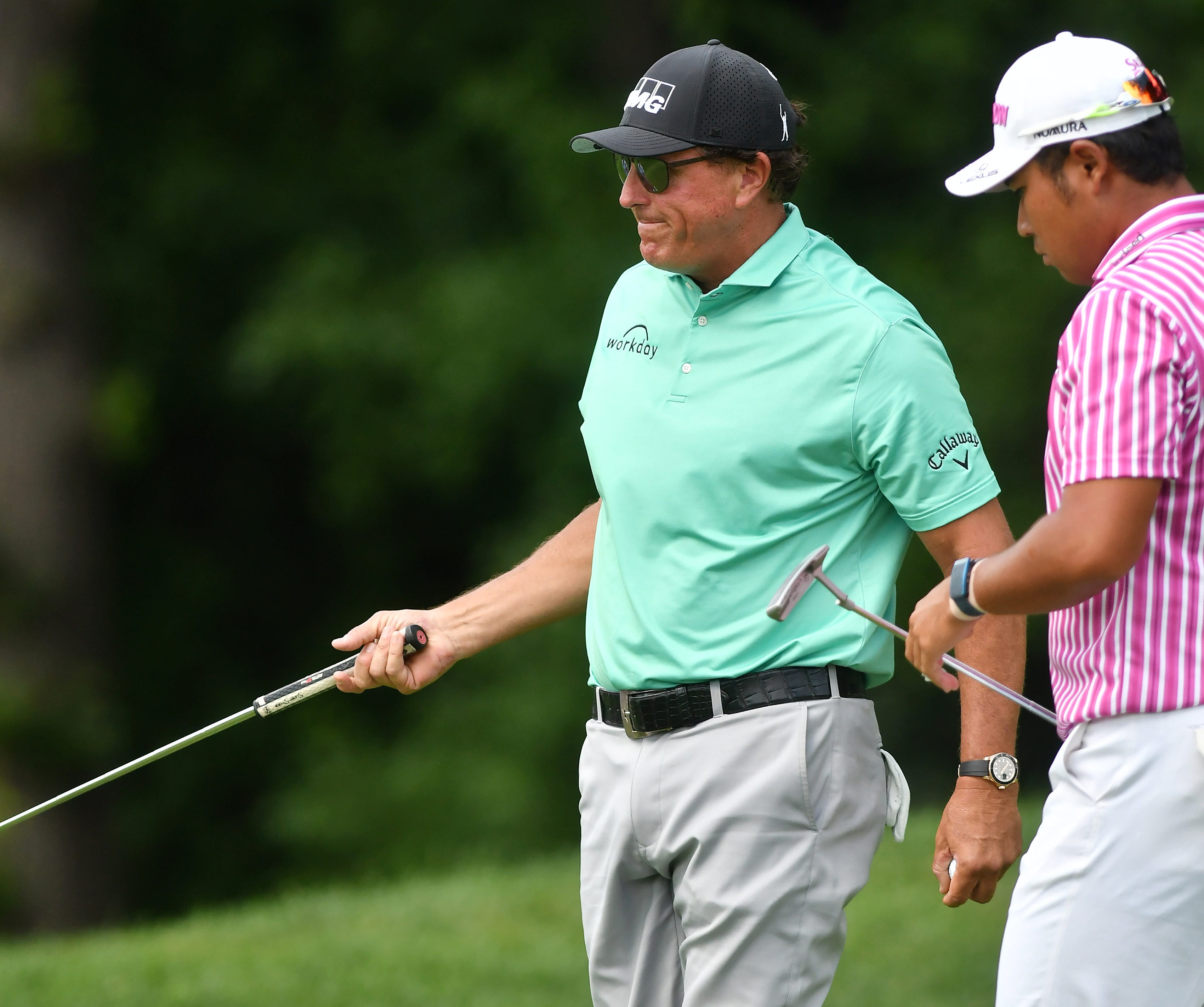 Phil Mickelson reacts after missing a putt on the ninth green next to Hideki Matsuyama, right.
