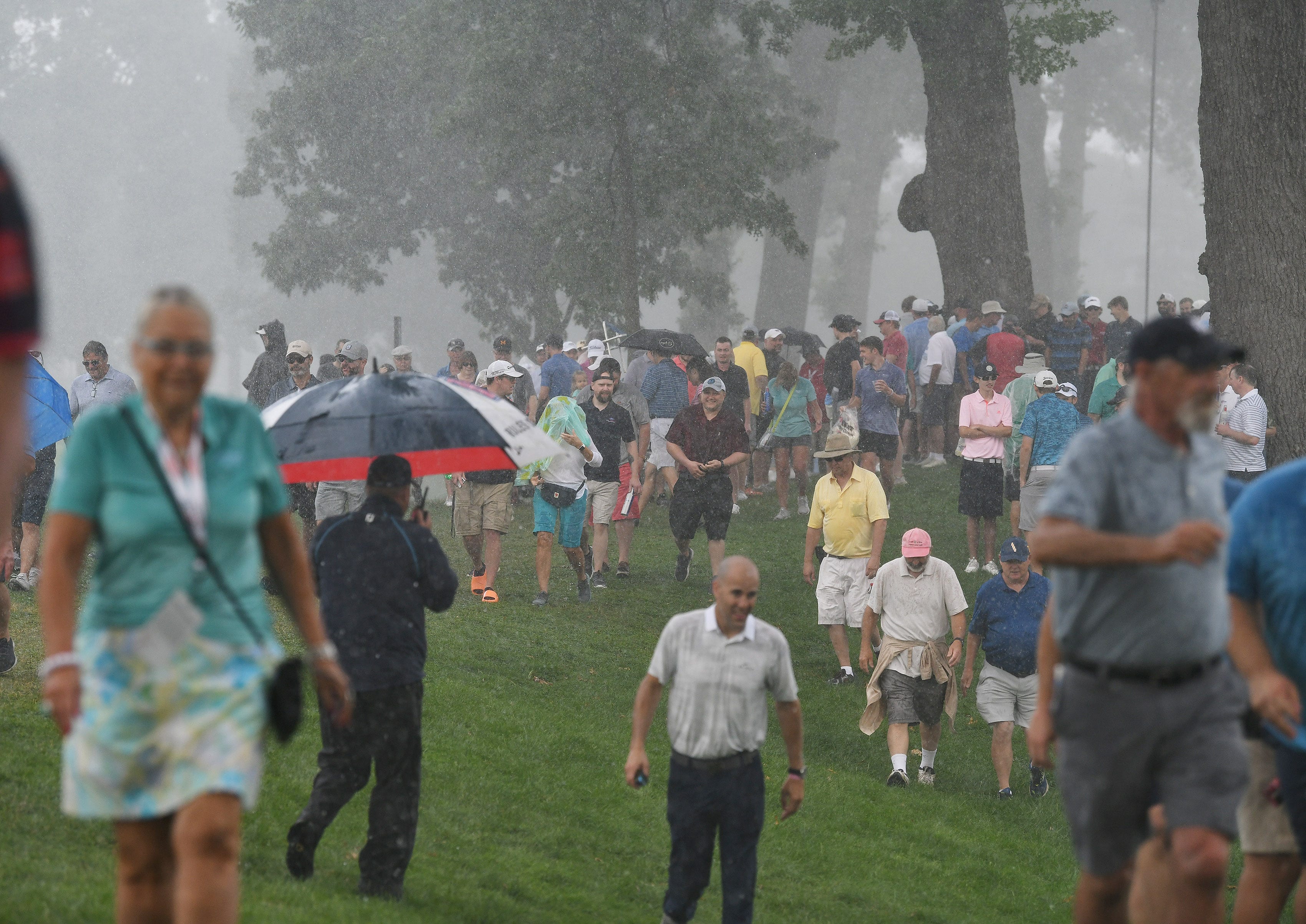 People start to head for cover after a heavy rain falls during Round 1 of the Rocket Mortgage Classic at the Detroit Golf Club.