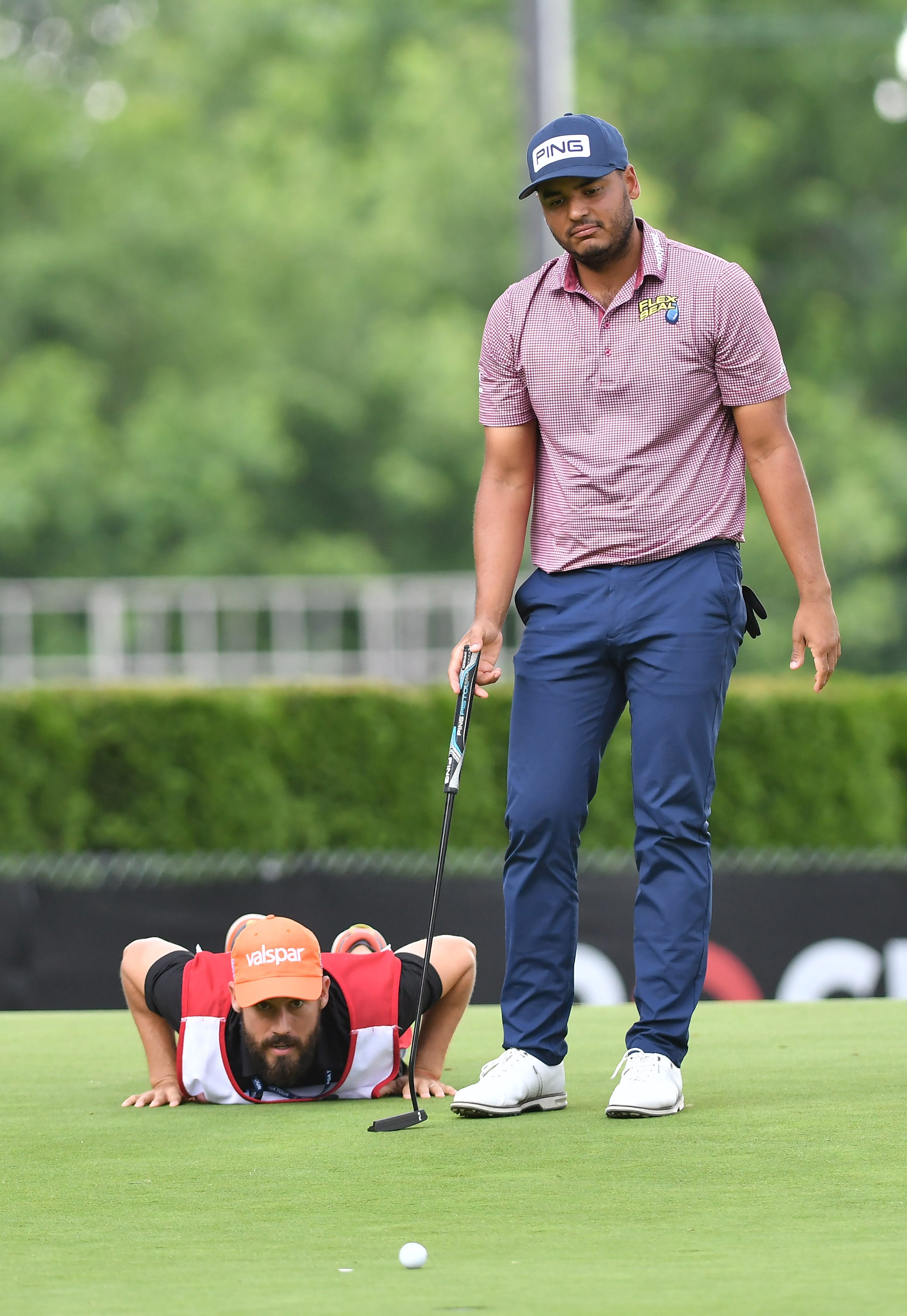 Sebastian Munoz looks over his putt with his caddie on the ninth green.