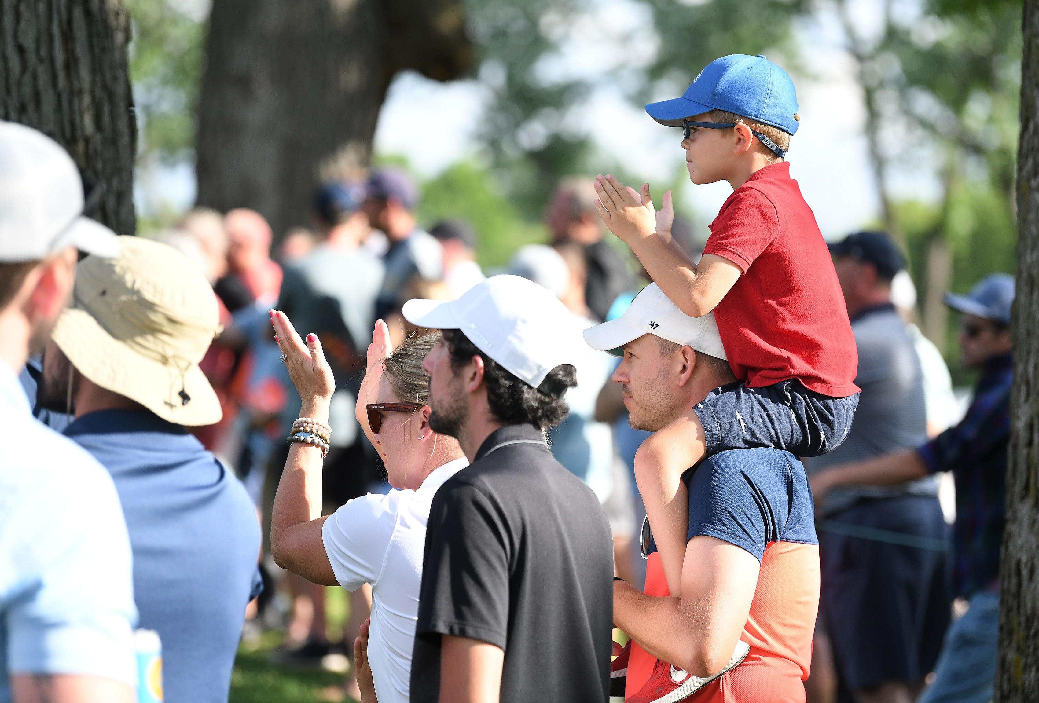 On the shoulders of his dad Kenny Laurence, 43, of Clarkston, Mikey Laurence (cq), 4, applauds with others at the 9th tee in Round 1.