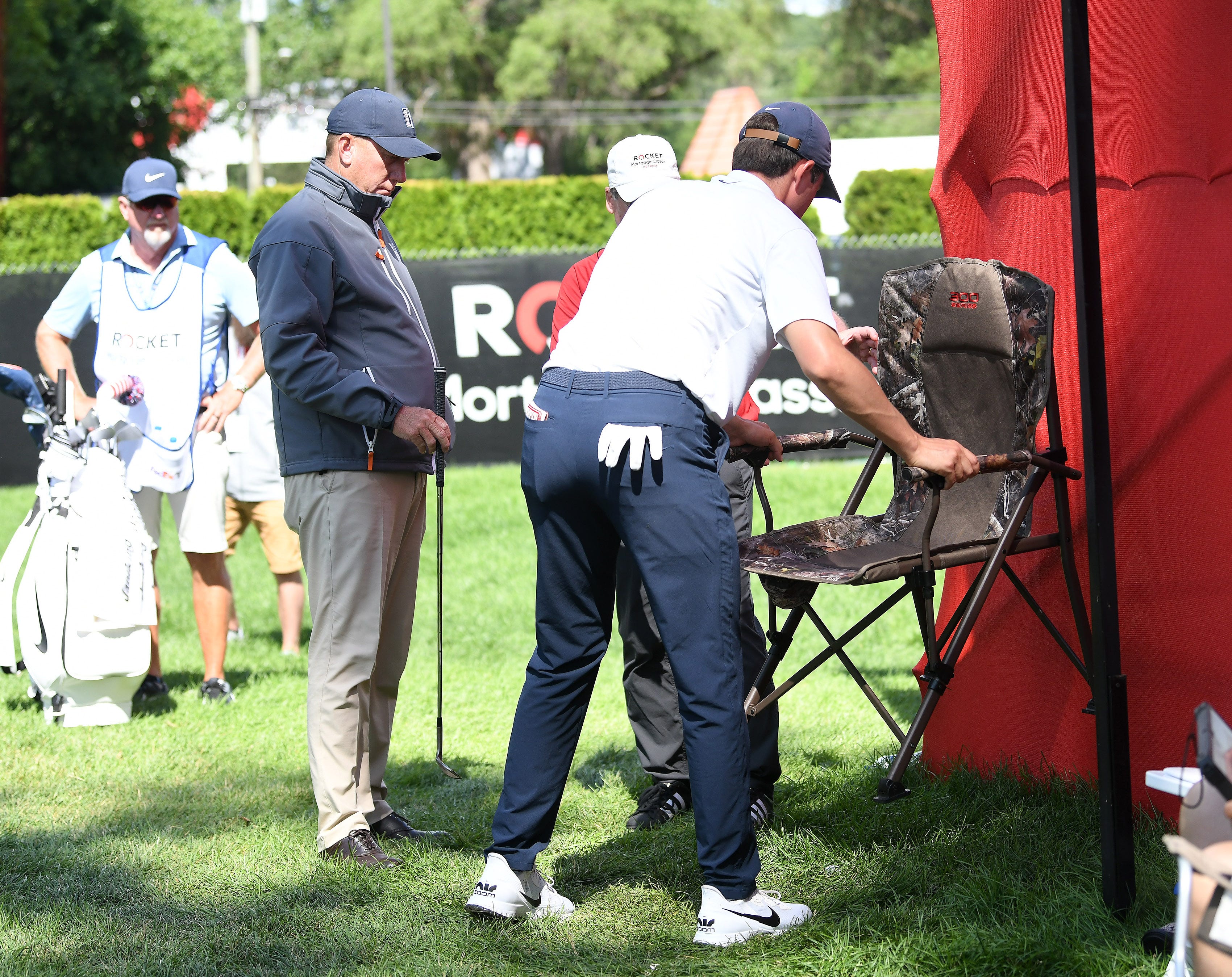 After consulting with PGA official, at left, Davis Thompson moves the chair that his ball rolled under on the ninth green.