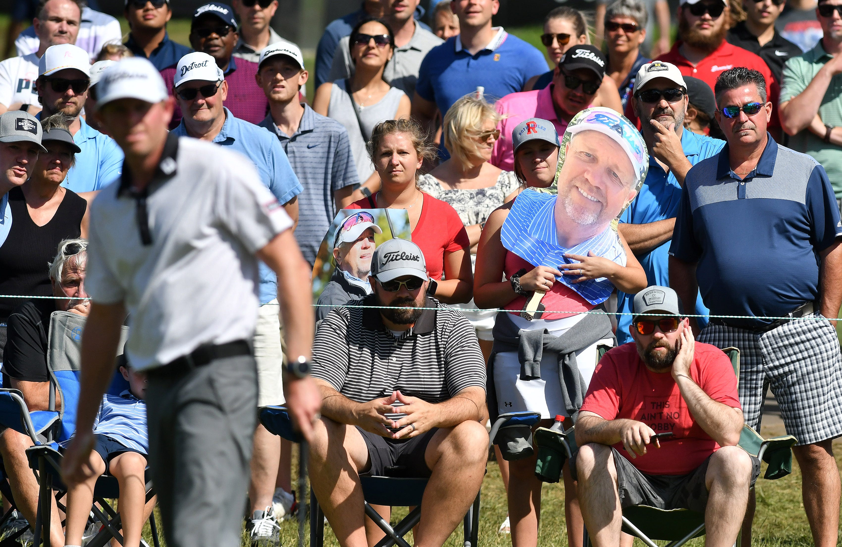 From left, sisters Megan Roth, 25, of Livonia and Michelle Roth, 27, of Farmington, New Mexico hold large photos of their dad, PGA player Jeff Roth, as he plays, not shown, on the 18th green.