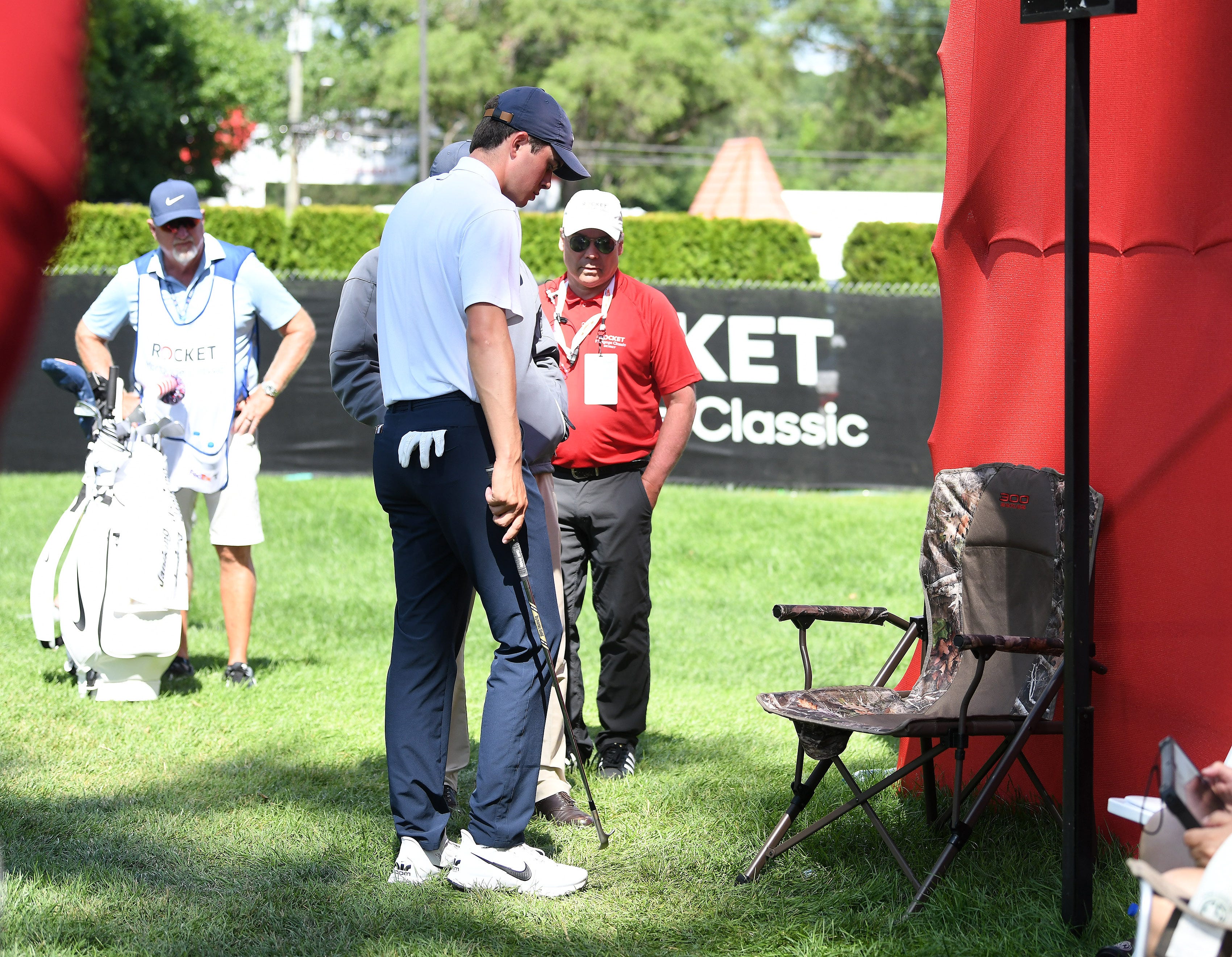Davis Thompson consults with a PGA official before moving the chair that his ball rolled under on the ninth green.