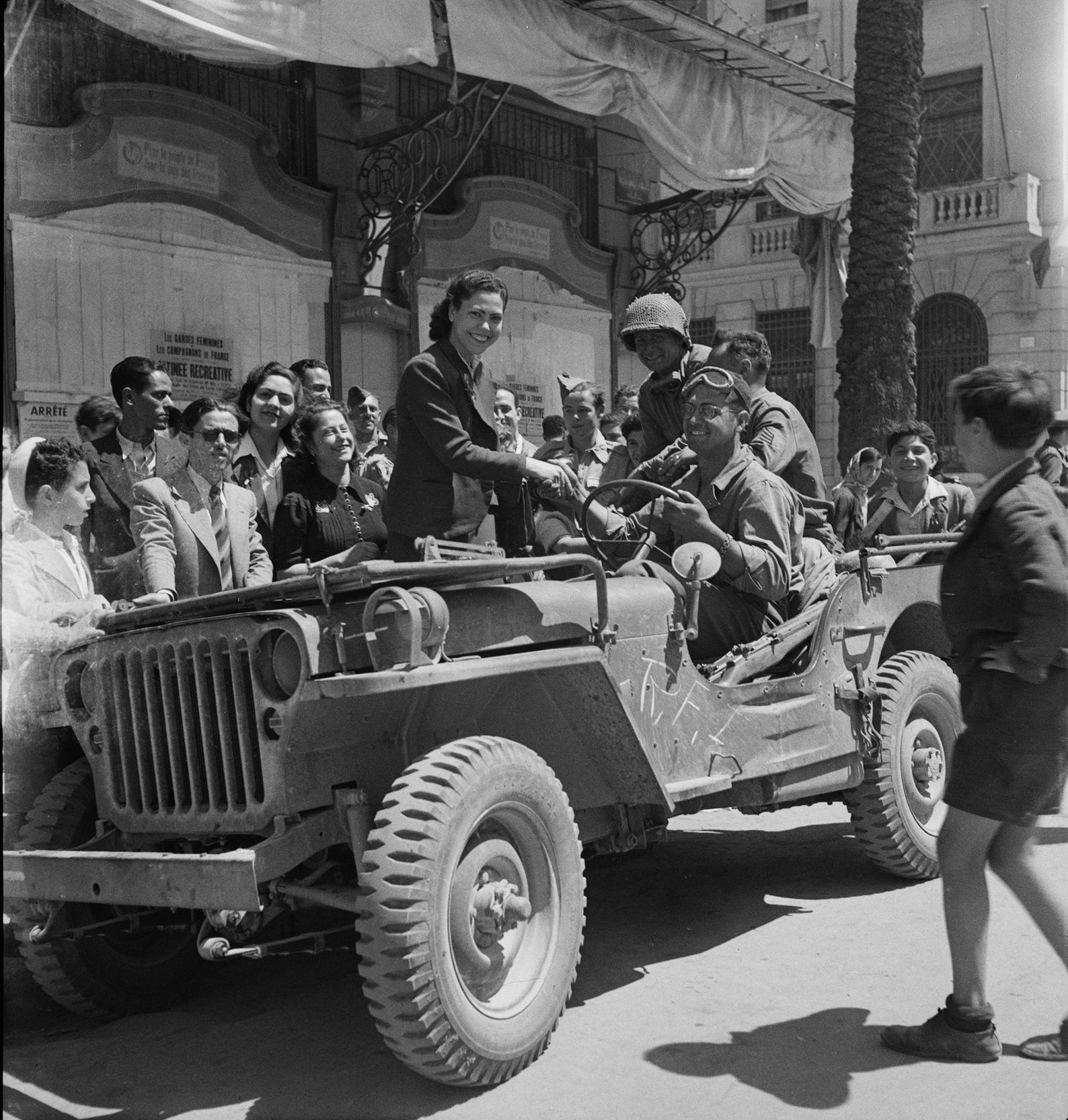 Girls climb on the Jeeps to greet American troops in the streets of Tunis in 1943.