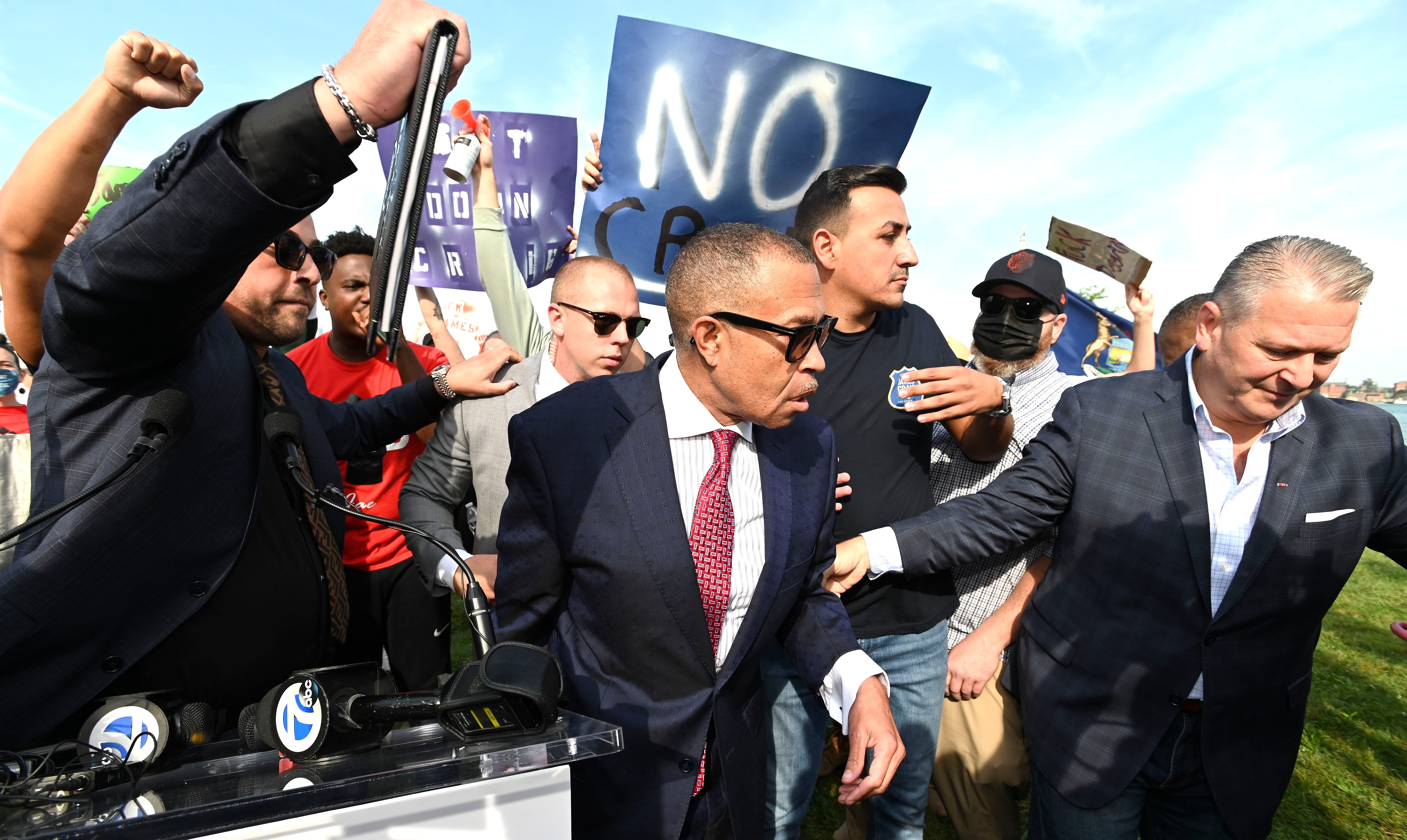 Former Detroit Police Chief James Craig is surrounded by staff and security personnel after he briefly announces his candidacy for governor at a podium on Belle Island amid the screams of protesters, Tuesday morning, September 14, 2021.