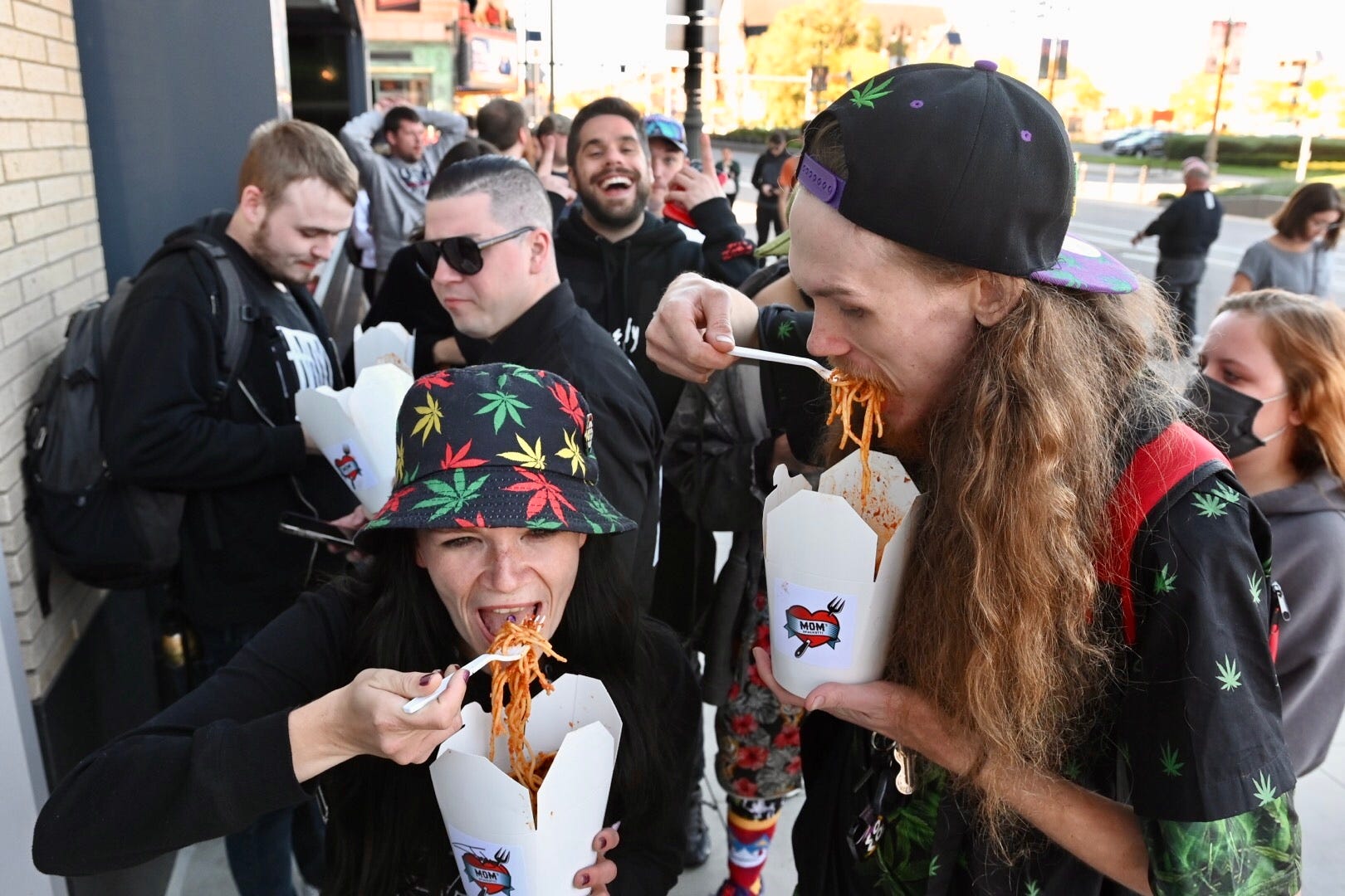 Erin Farrer, left, of Detroit and her cousin Joel Farrer enjoy Mom's Spaghetti outside during the opening of rapper Eminem's restaurant in downtown Detroit on Wednesday, September 29, 2021.