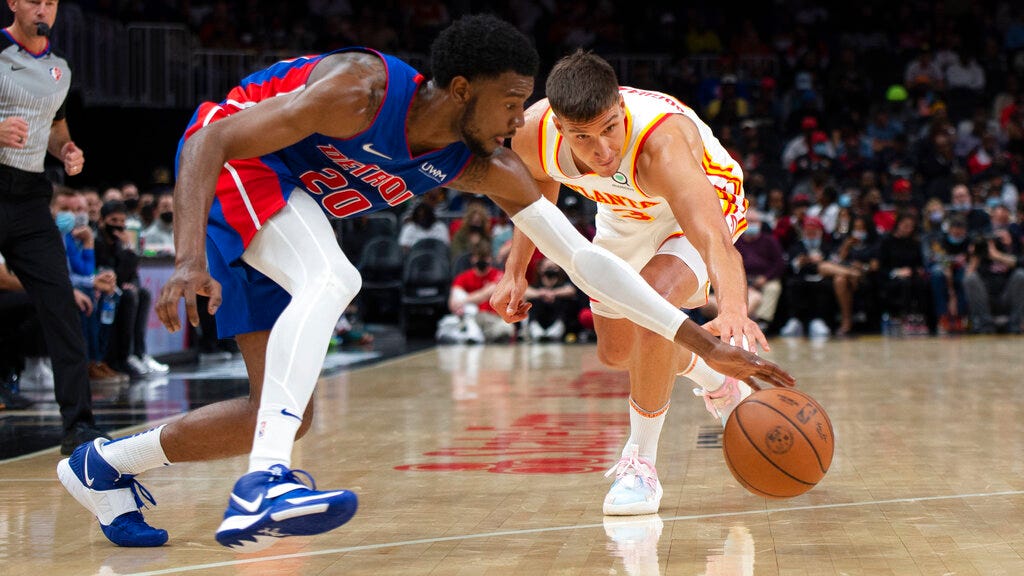 Pistons guard Josh Jackson (20) and Hawks guard Bogdan Bogdanovic (13) reach for the ball during the second half of Monday's NBA game in Atlanta.