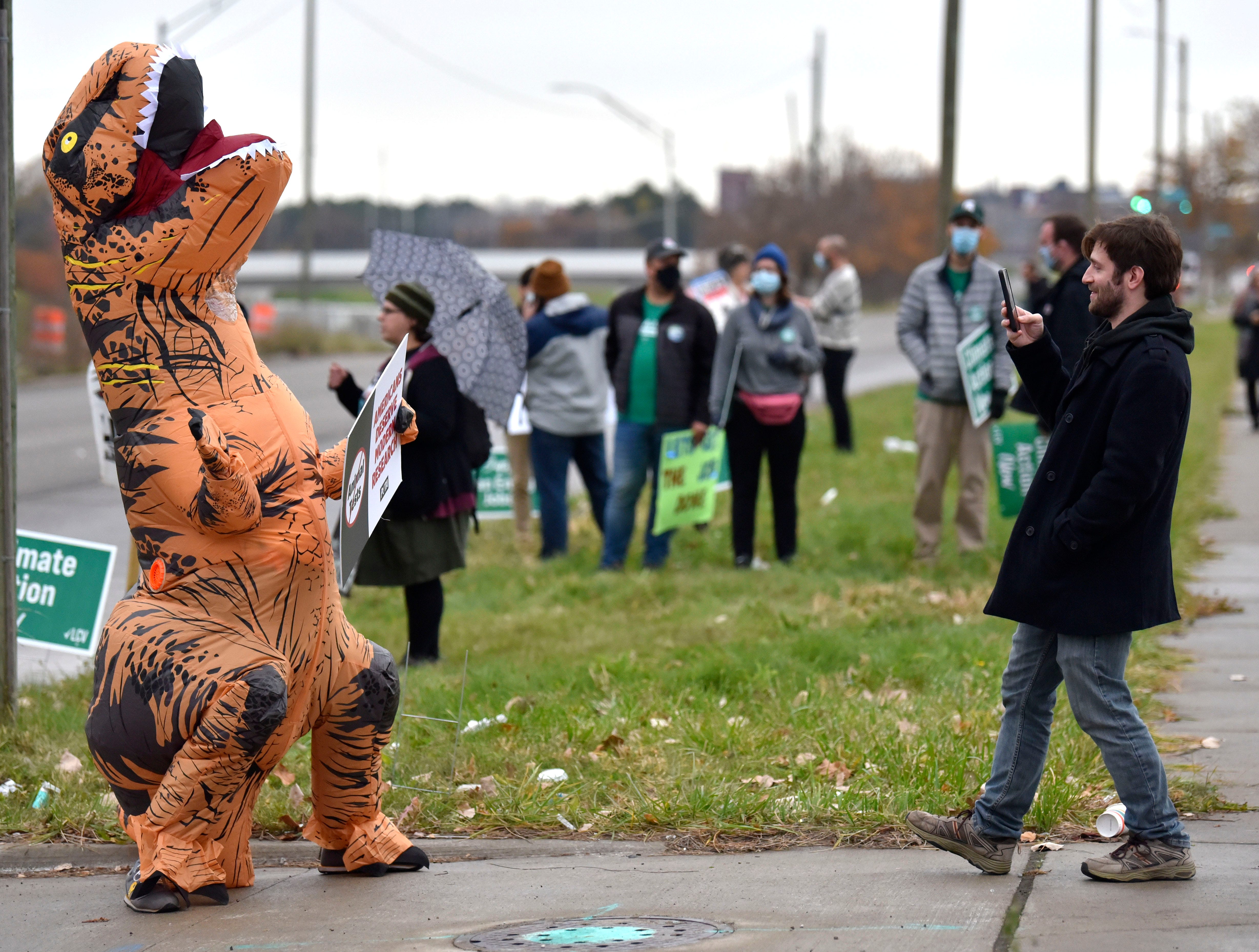 PETA member Sarah Terrien, of Hamtramck, wears an inflatable dinosaur during the protest, Wednesday afternoon, November 17, 2021. 
\Members of Oil & Water Don't Mix Keep Oil Out of the Great Lakes and others protest Enbridge's twin Line 5 oil pipelines in the Straits of Mackinac before President Joe Biden tours the GM Factory ZERO in Detroit.