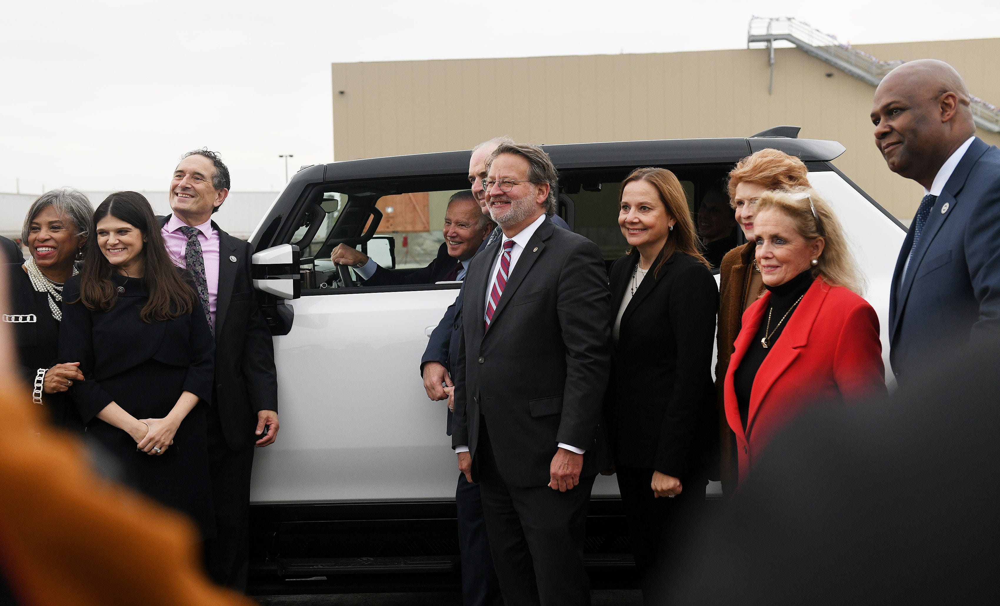 Behind the wheel, President Joe Biden is photographed with Washington lawmakers from Michigan, from left, Brenda Lawrence, Haley Stevens, Andy Levin, Dan Kildee, Gary Peters, GM CEO Mary Barra, Debbie Stabenow, Debbie Dingell and UAW Pres. Ray Curry at the General Motors Factory ZERO in Detroit  on Nov. 17, 2021.