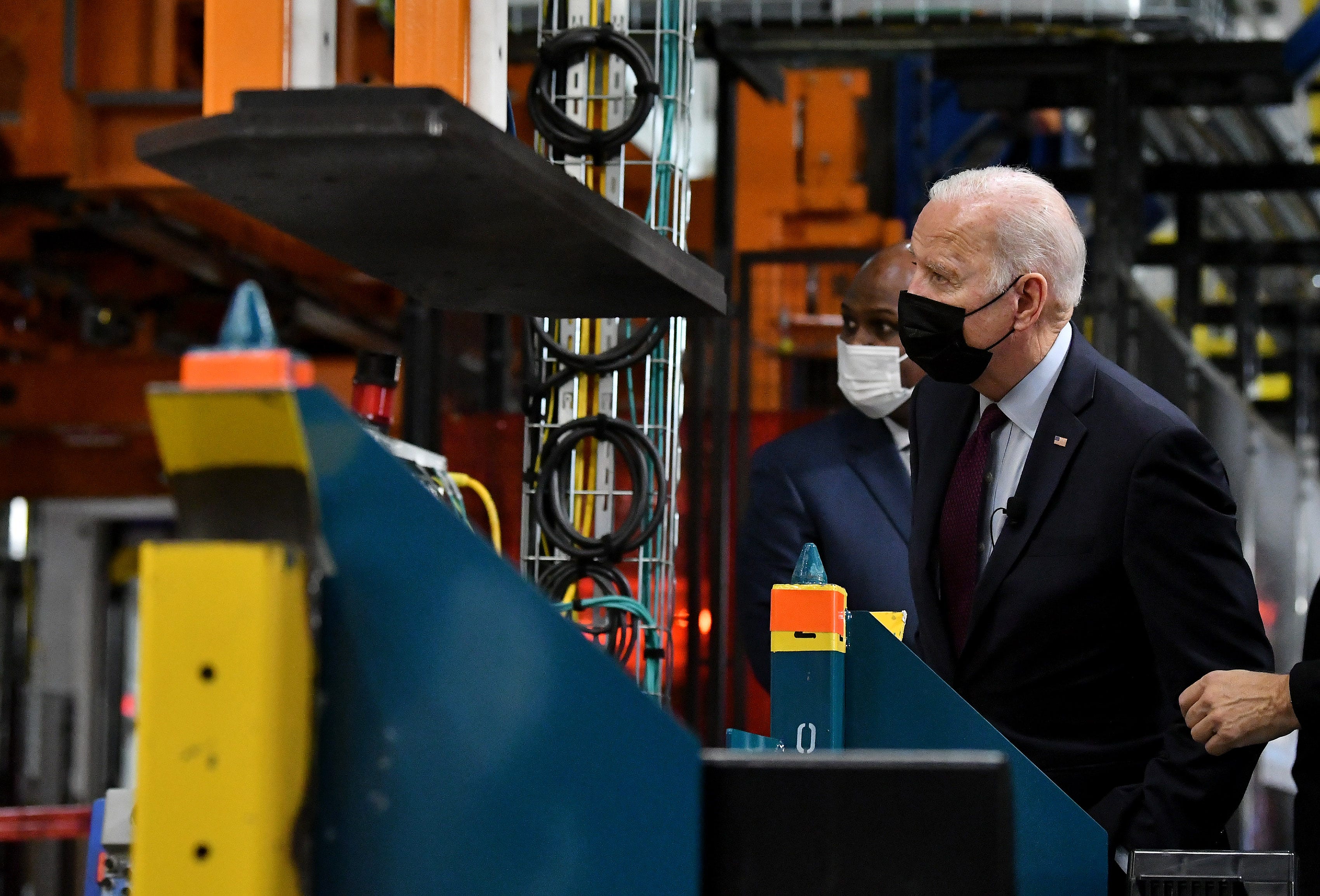 President Joe Biden, right, with UAW President Ray Curry, left, watches a battery be joined to the frame of a Hummer EV.