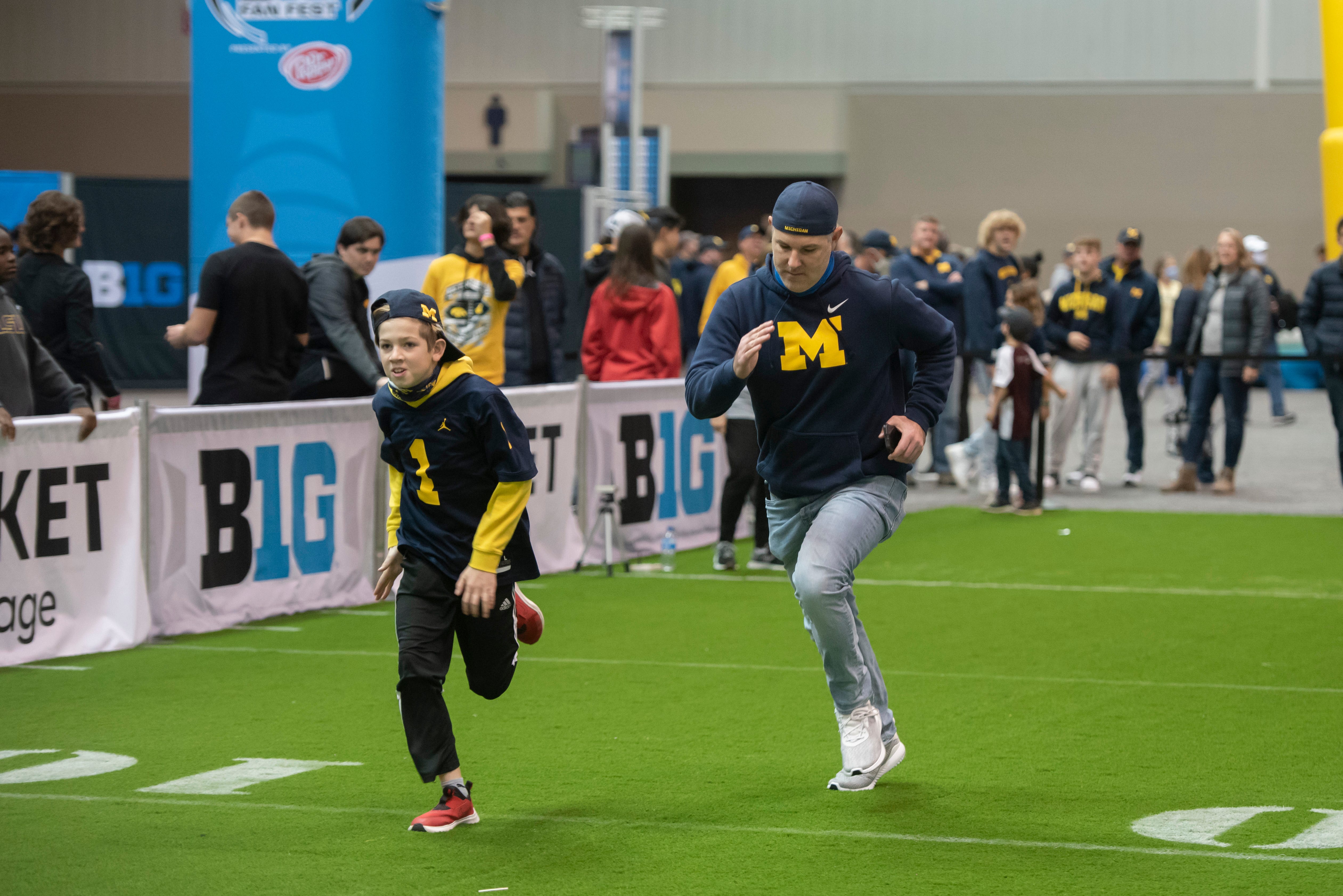 Eleven-year-old Grayson Cichelli, of Chicago, and his father Chris, a Troy native, run a 40-yard-dash at the Fan Fest at the Indiana Convention Center, before the start of the Big Ten championship game.