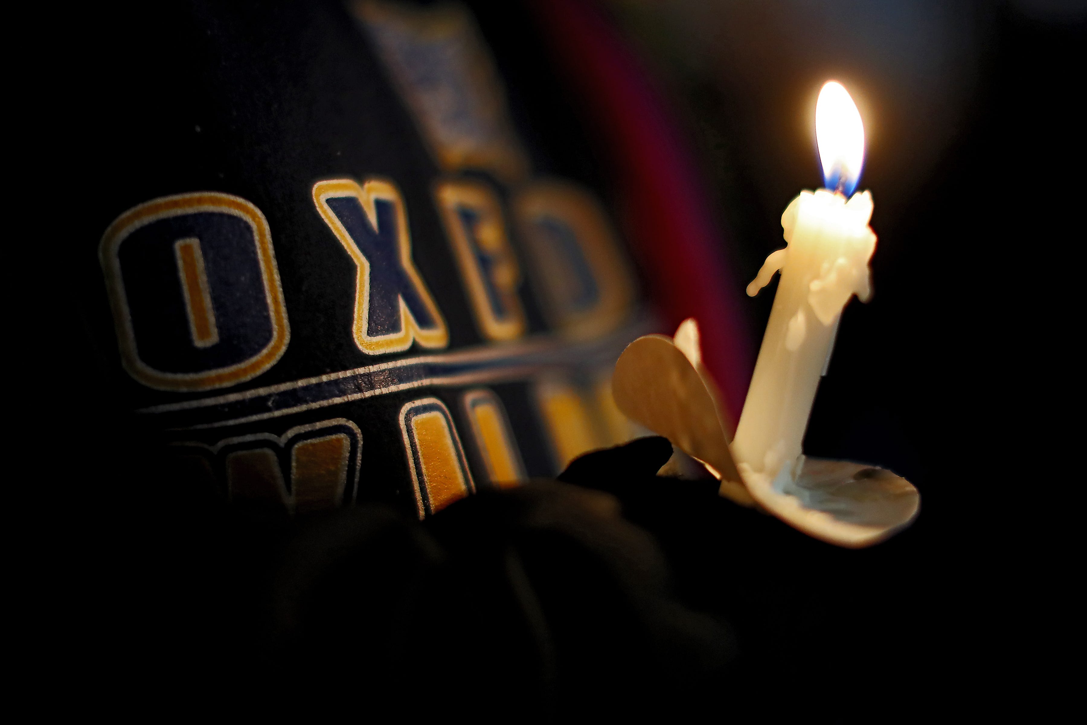 A young student takes part in a candlelight vigil on Friday, Dec. 3, 2021 in downtown Oxford.