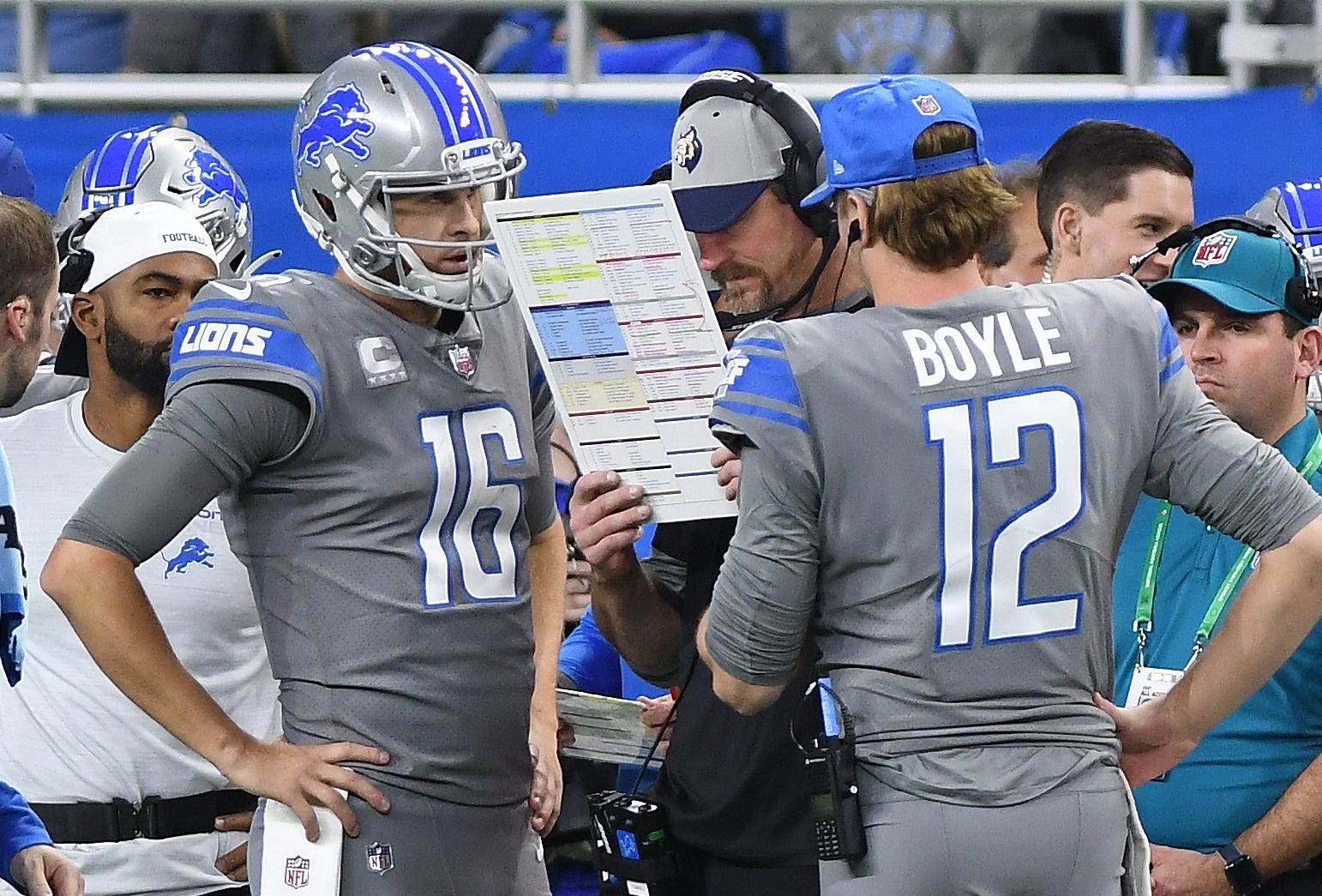 Lions quarterbacks Jared Goff and Tim Boyle work with coach Dan Campbell on the sideline during a break in the action in the fourth quarter.