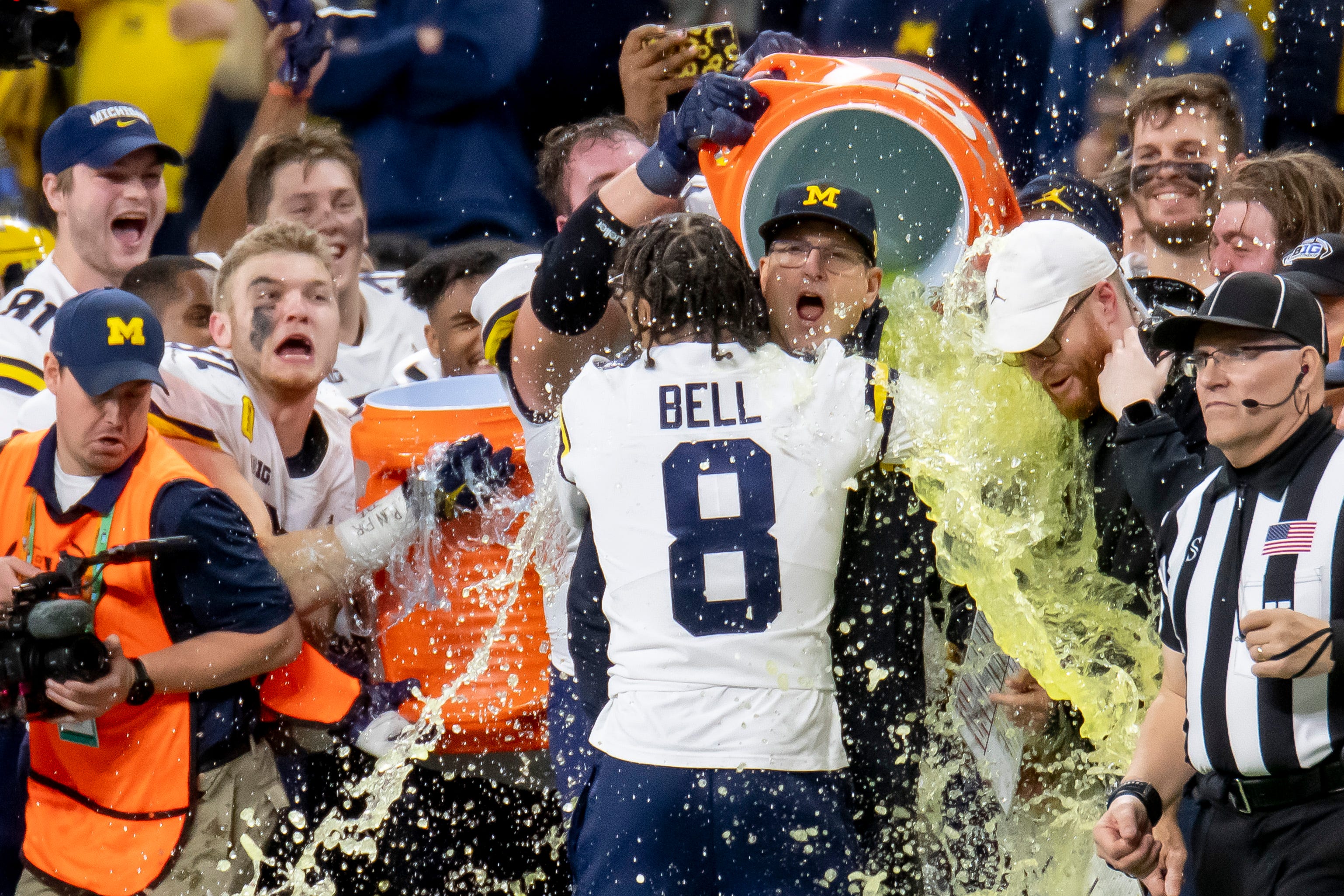 While getting a hug from wide receiver Ronnie Bell, head coach Jim Harbaugh gets doused with Gatorade during the final moments of the fourth quarter. Michigan defeated Iowa, 42-3, in the Big Ten Championship Game, December 4, 2021, at Indianapolis.