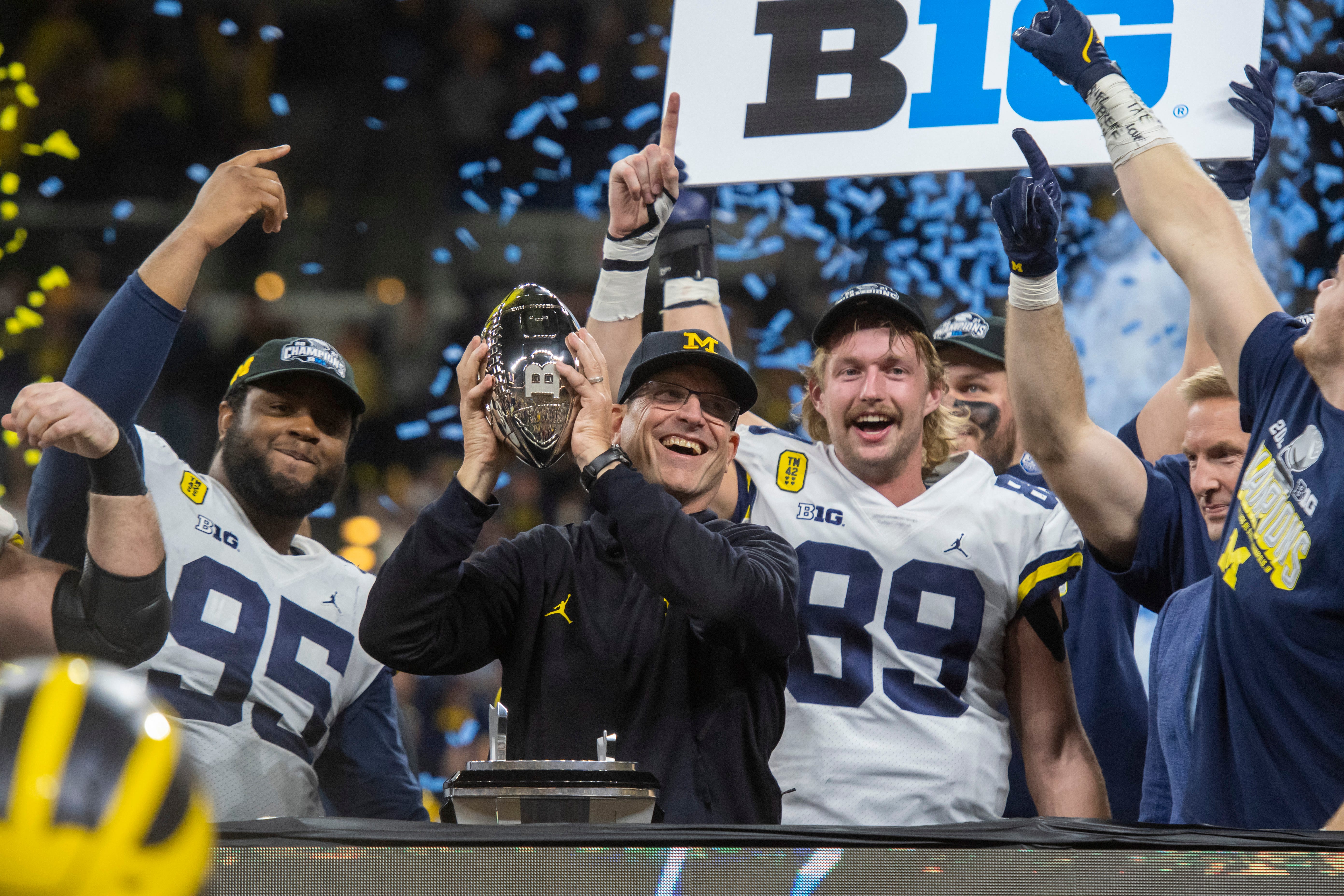 Head coach Jim Harbaugh holds up the championship trophy after the University of Michigan defeated the University of Iowa 42-3 to win the Big Ten championship at Lucas Oil Stadium in Indianapolis, December 5, 2021.