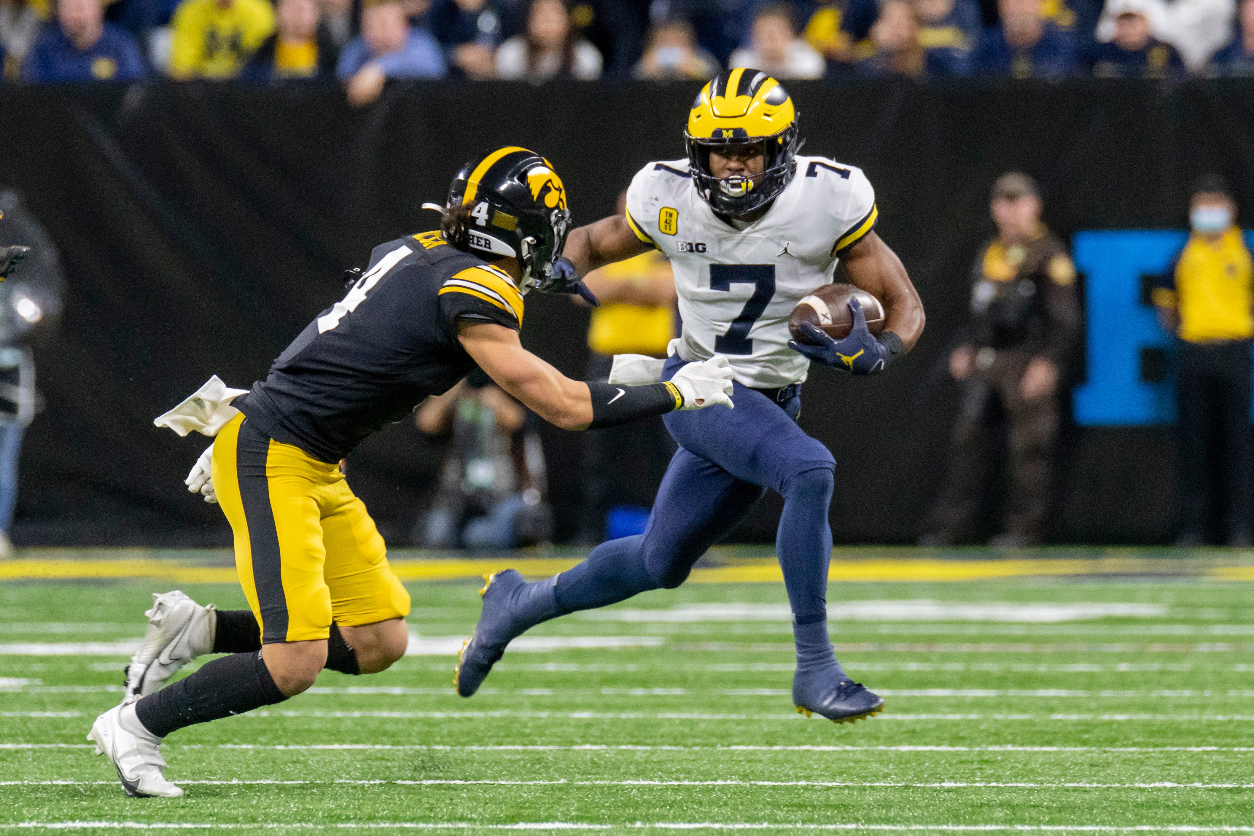 Michigan running back Donovan Edwards runs the ball away from Iowa defensive back Dane Belton during the second quarter.