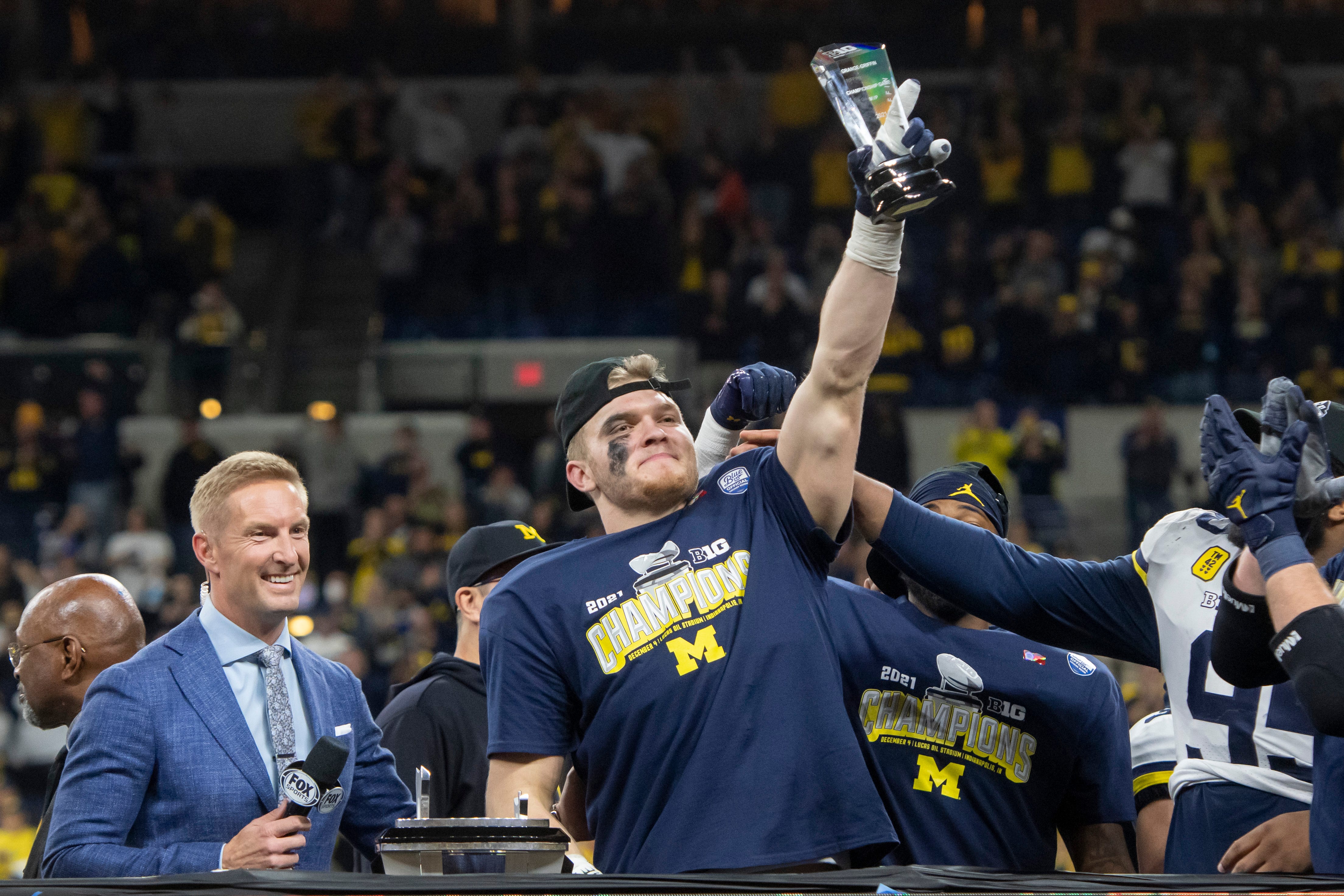 Michigan defensive end Aidan Hutchinson holds up the game MVP trophy after the University of Michigan defeated the University of Iowa 42-3 to win the Big Ten championship.