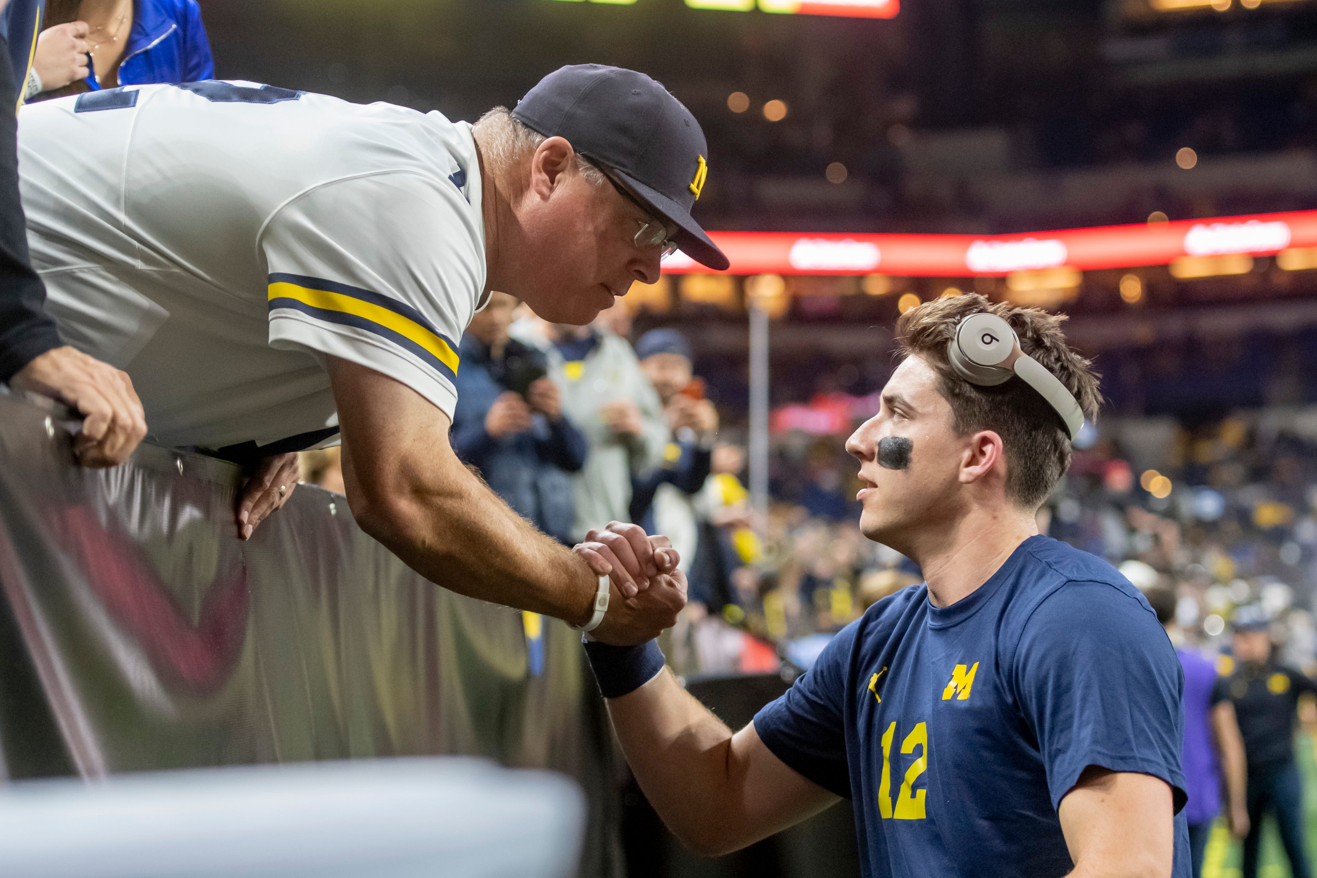 Michigan quarterback Cade McNamara, right, gets a handshake from his dad Gary before the start of the Big Ten championship game at Lucas Oil Stadium in Indianapolis, December 4, 2021.