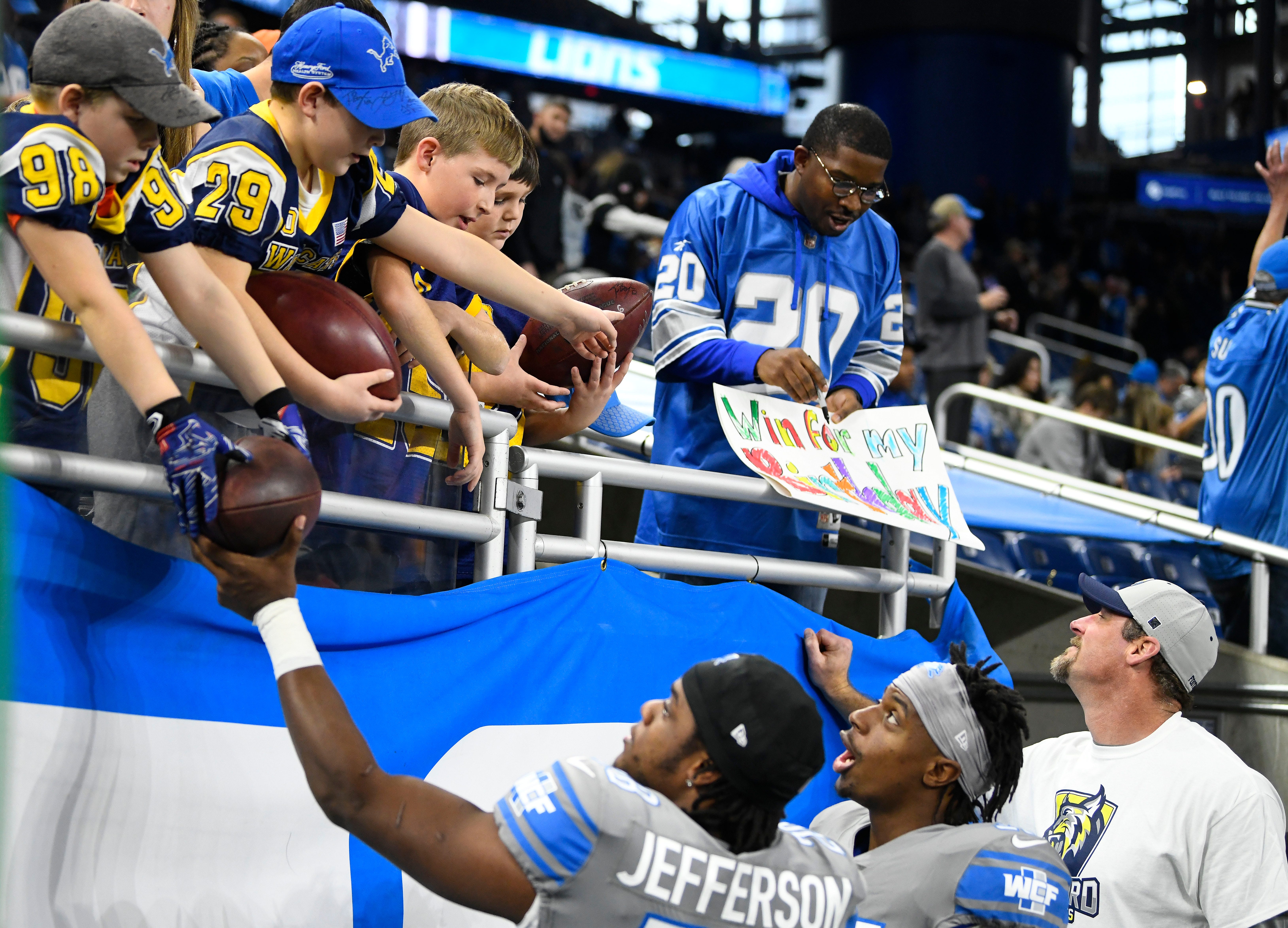 Detroit Lions players Jermar Jefferson, Jerry Jacobs and head coach Dan Campbell sign autographs for members of the Oxford Jr. Wildcats football team during warmups before the game against the  Minnesota Vikings at Ford Field in Detroit, Michigan on December 5, 2021.