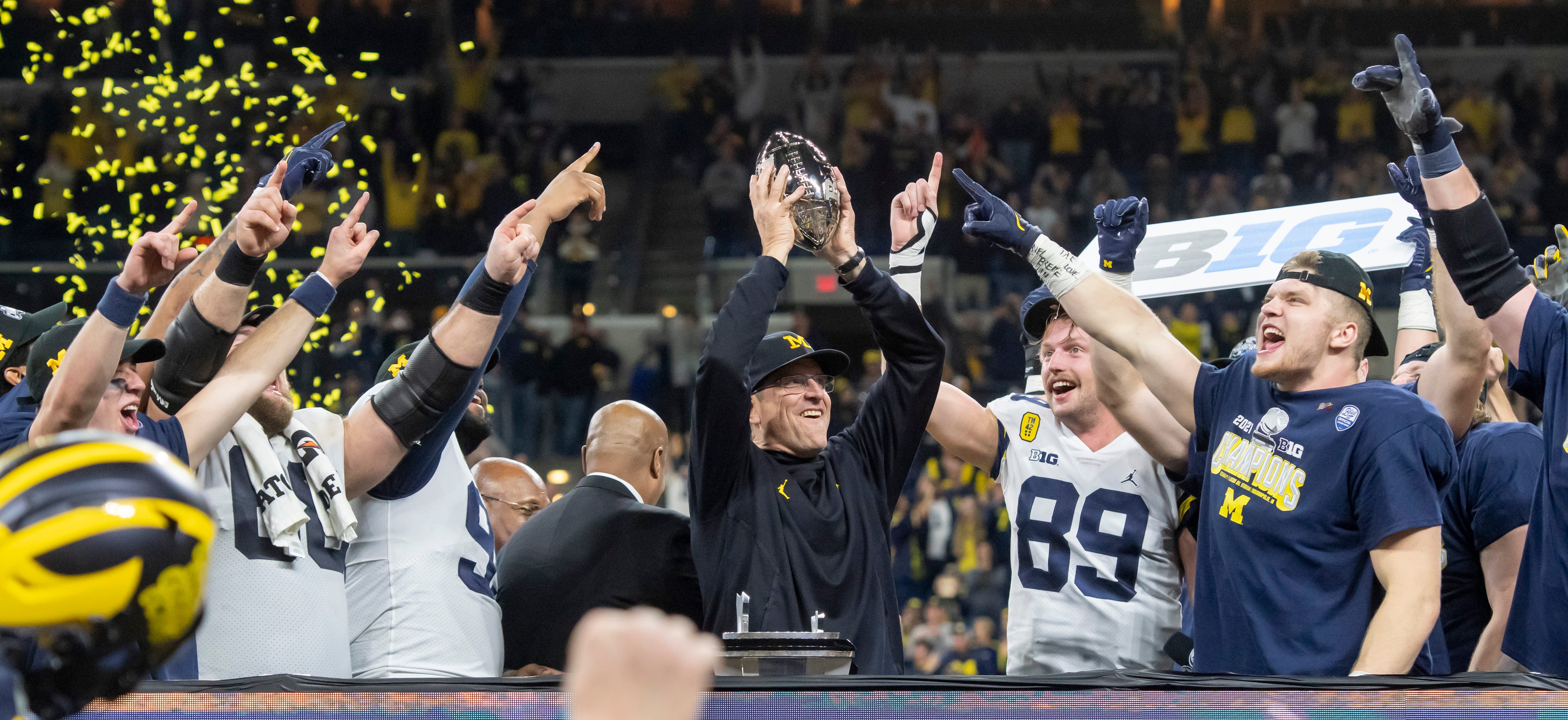 Head coach Jim Harbaugh holds up the championship trophy after the University of Michigan defeated the University of Iowa 42-3 to win the Big Ten championship.