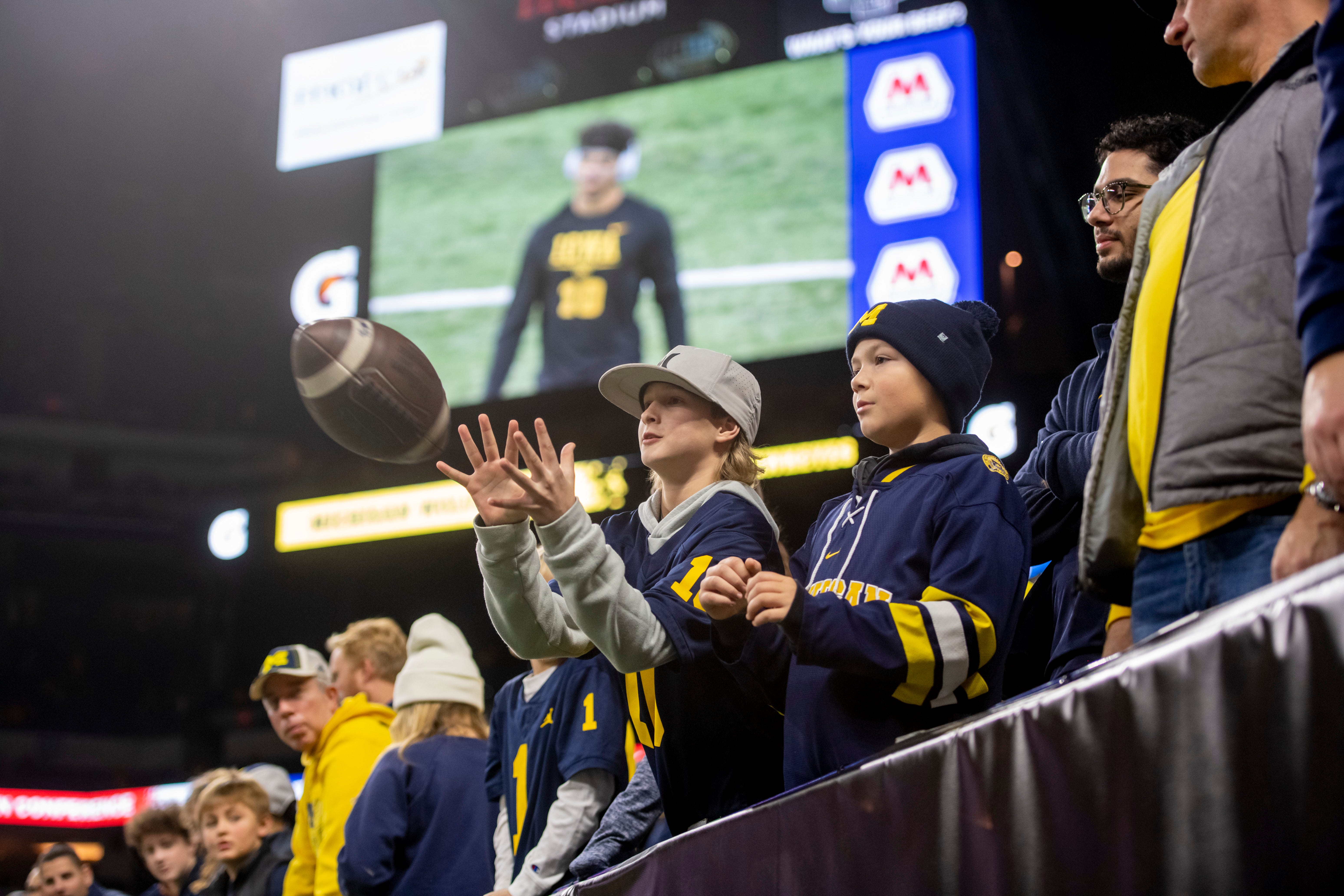 A young fan catches a pass before the start of the Big Ten championship game at Lucas Oil Stadium.