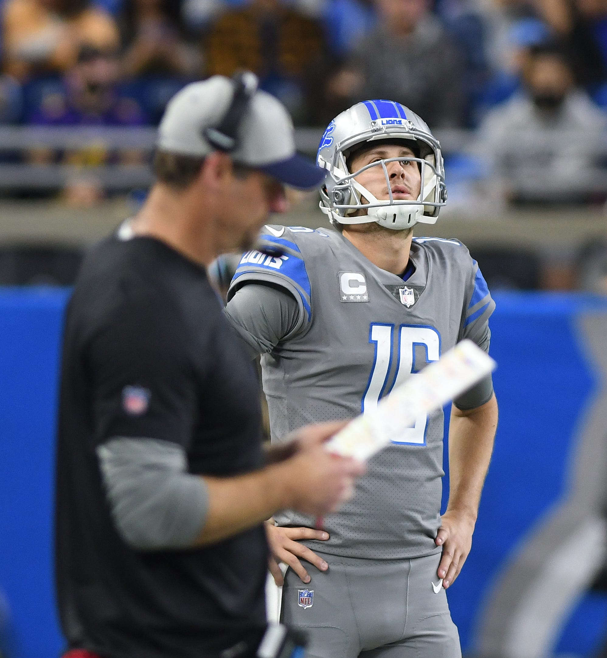 Lions quarterback looks up at the video board while working with head coach Dan Campbell in the third quarter.
