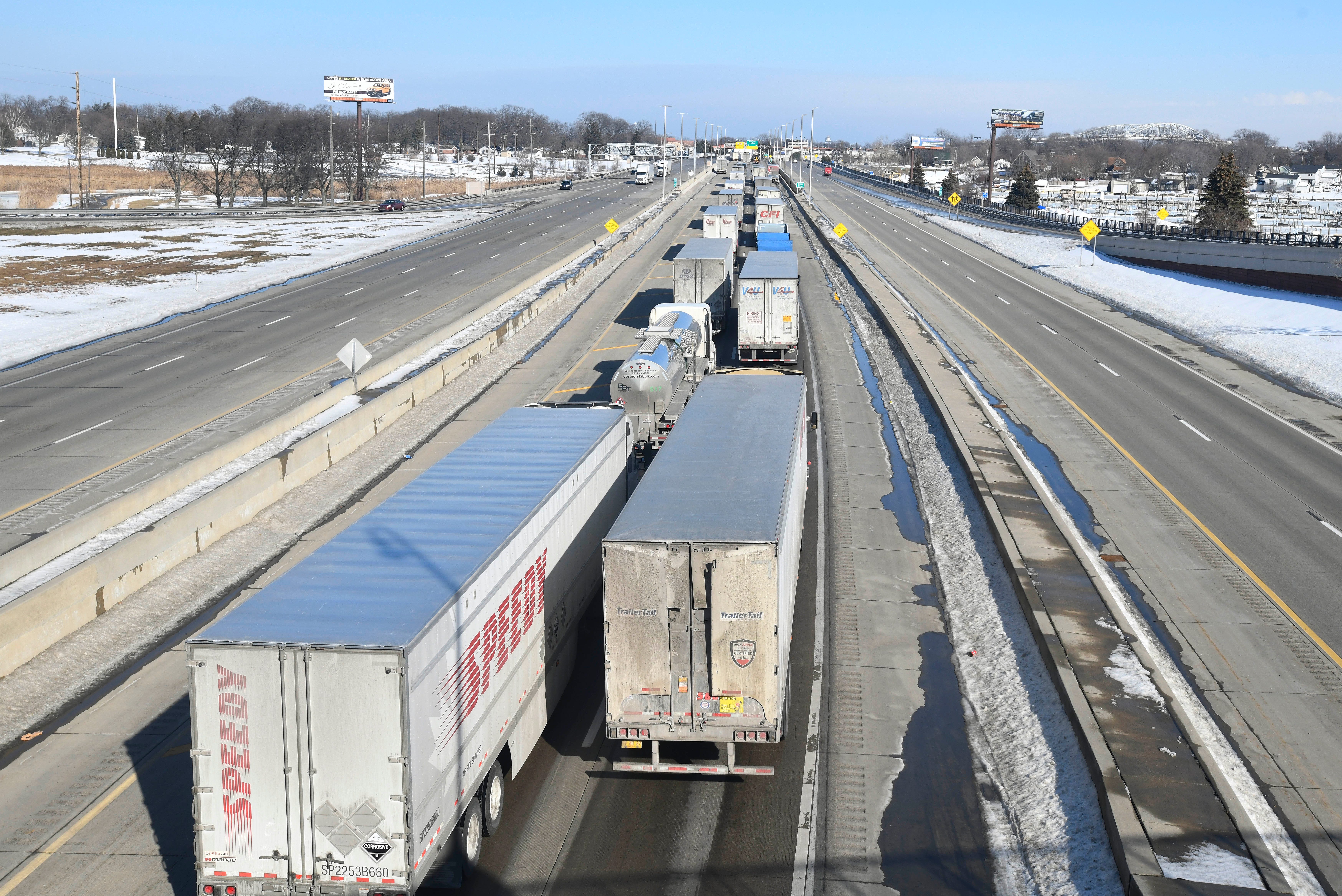 Trucks lined up along I-69 for the Blue Water Bridge, seen in the upper right, in Port Huron, Michigan on February 9, 2022.