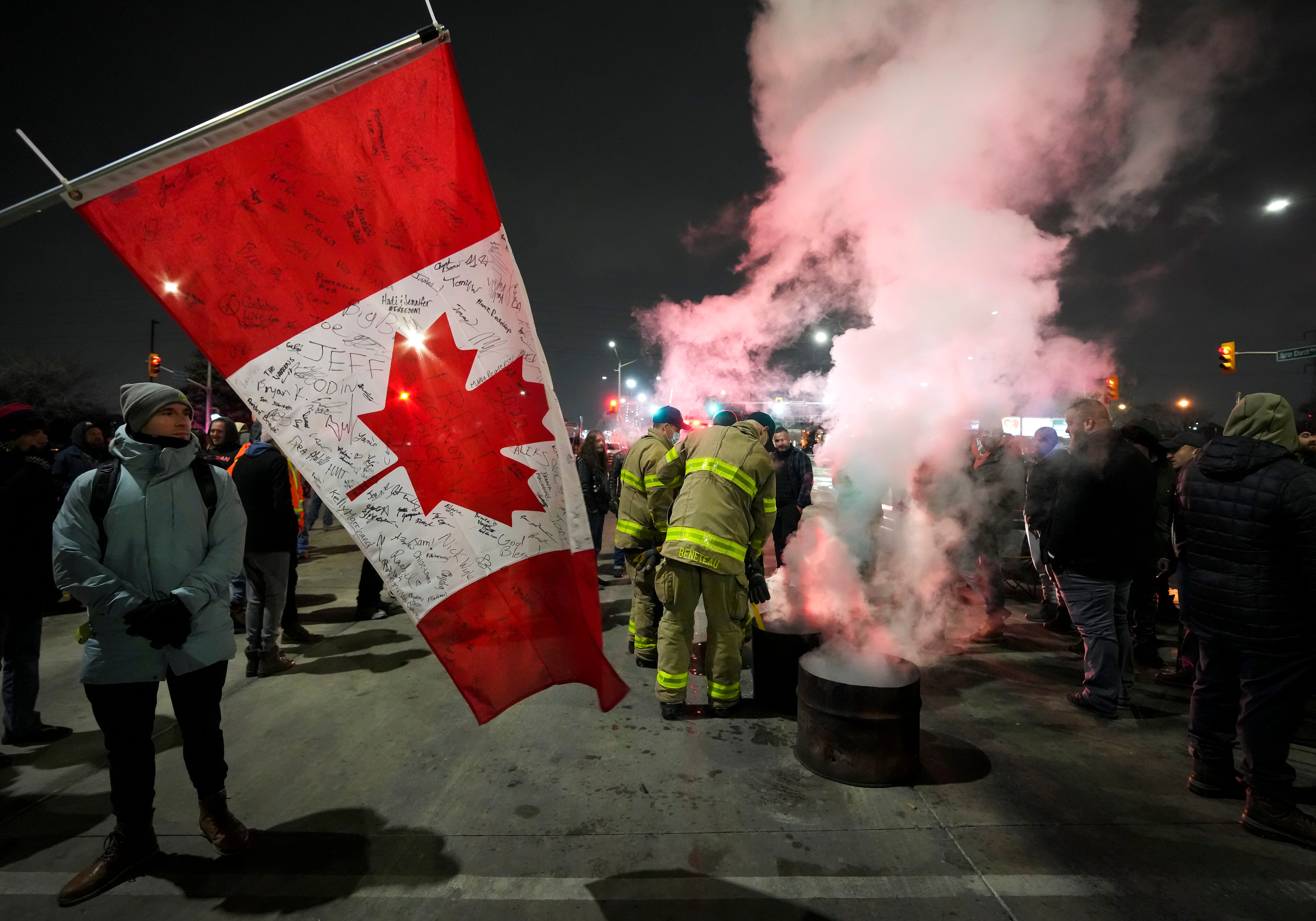 Firefighters put out a burning barrel fire as truckers and supporters block the access leading from the Ambassador Bridge, linking Detroit and Windsor, as truckers and their supporters continue to protest against the COVID-19 vaccine mandates and restrictions in Windsor, Ontario, on Wednesday, Feb. 9, 2022.