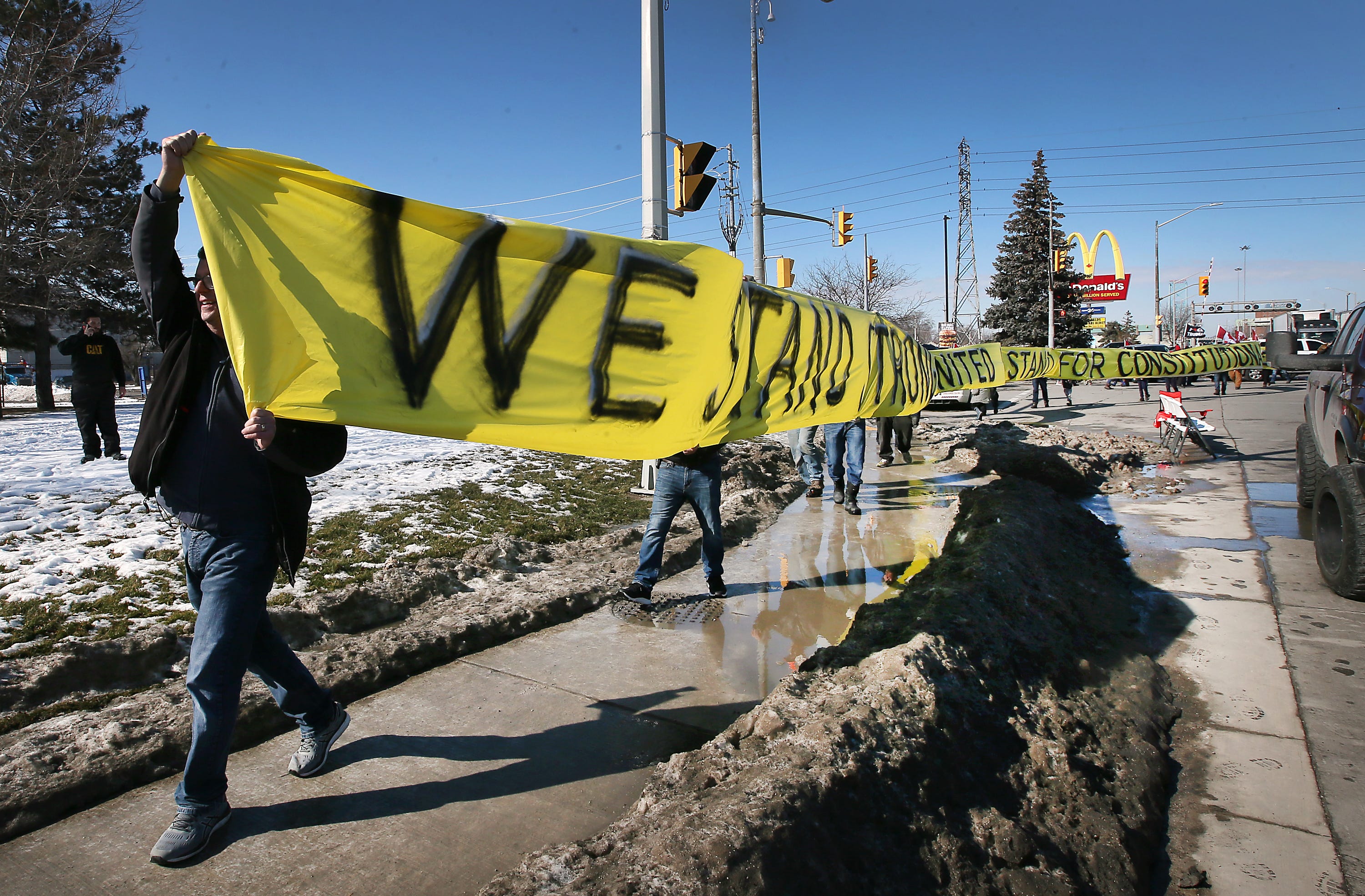 Anti vaccine mandate protestors march with a banner near the Ambassador Bridge in Windsor on Wednesday, February 9, 2022.