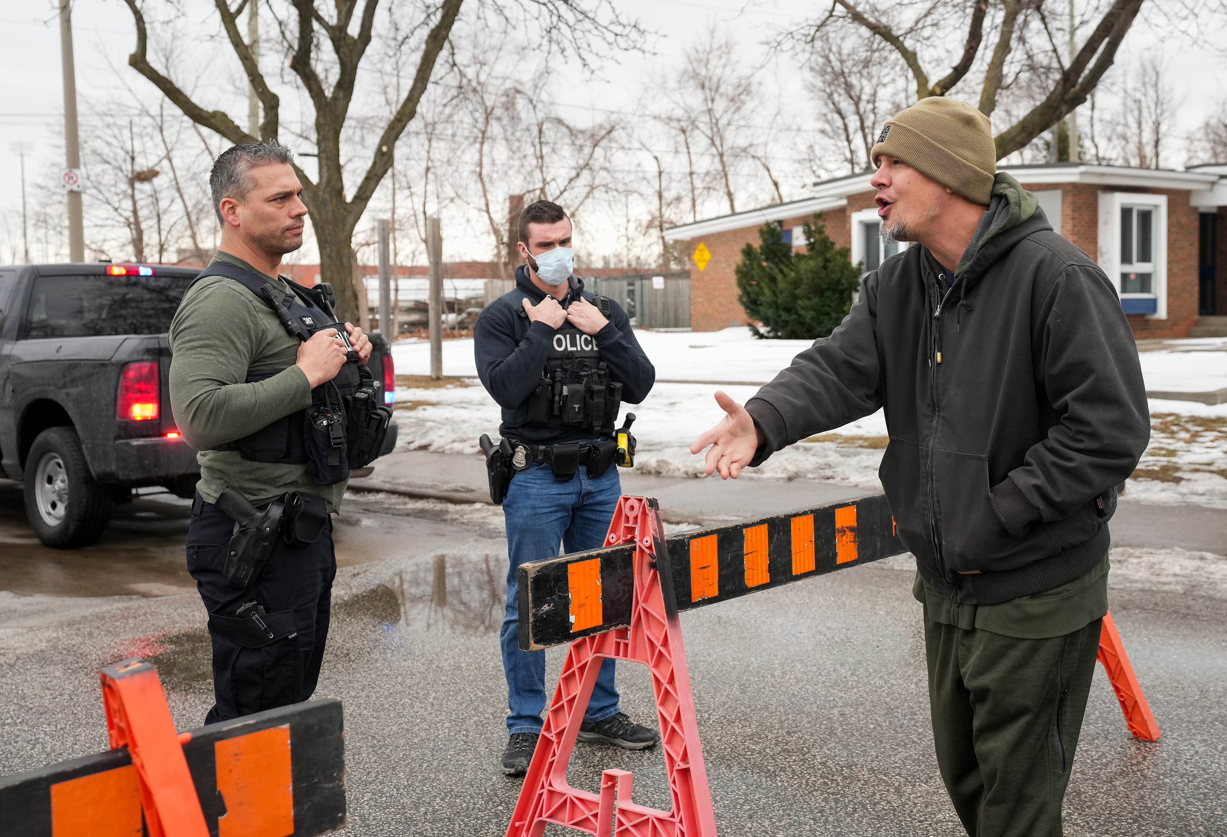 A trucker supporter, right, argues with police for not allowing his truck through as truckers and supporters block the access leading from the Ambassador Bridge, linking Detroit and Windsor, during a protest against COVID-19 vaccine mandates and restrictions, in Windsor, Ont., Thursday, Feb. 10, 2022.