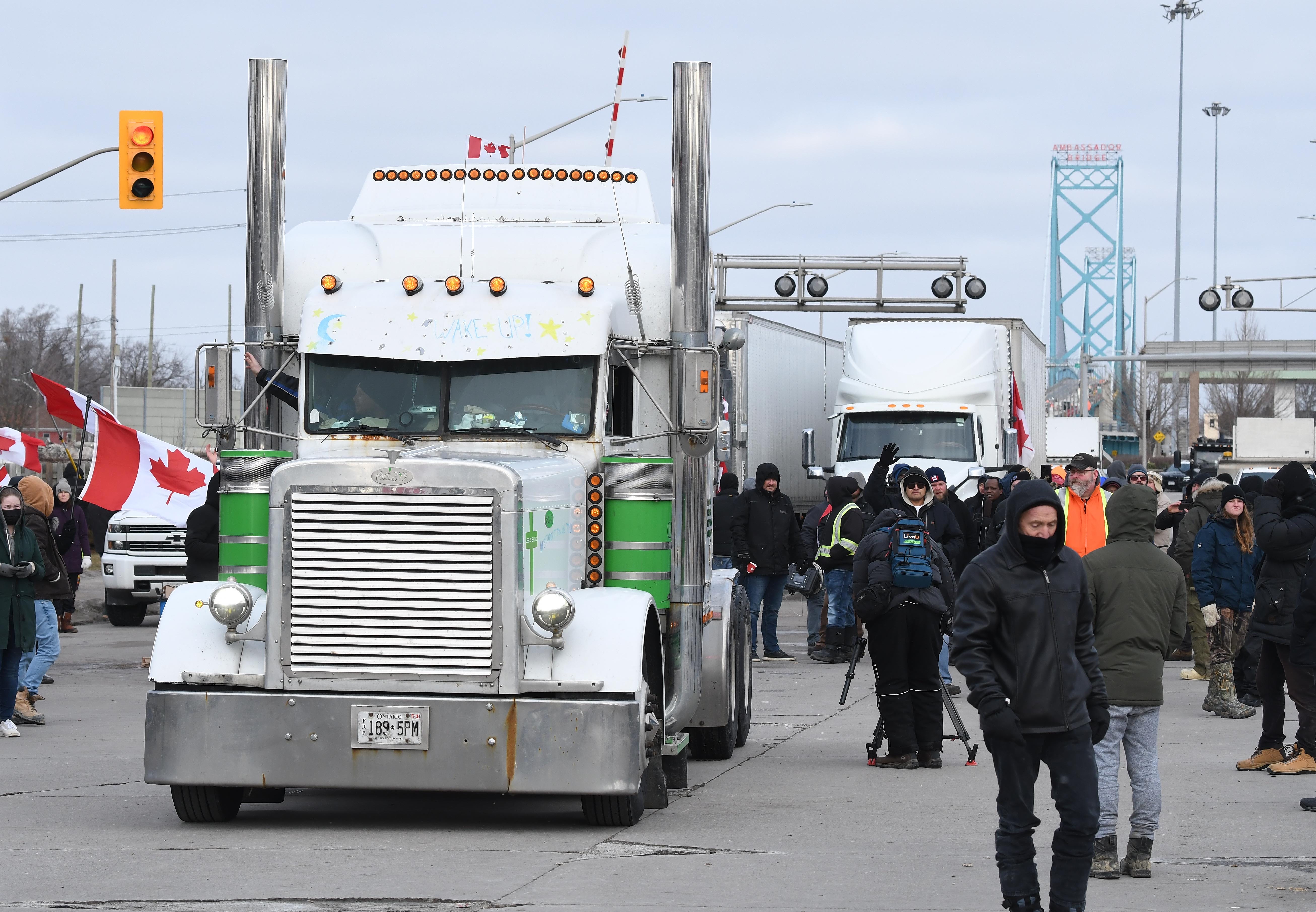Semi trucks are moved down the road by police, opening the road to the Ambassador bridge in Windsor, Ontario, on Saturday, February 12, 2022.