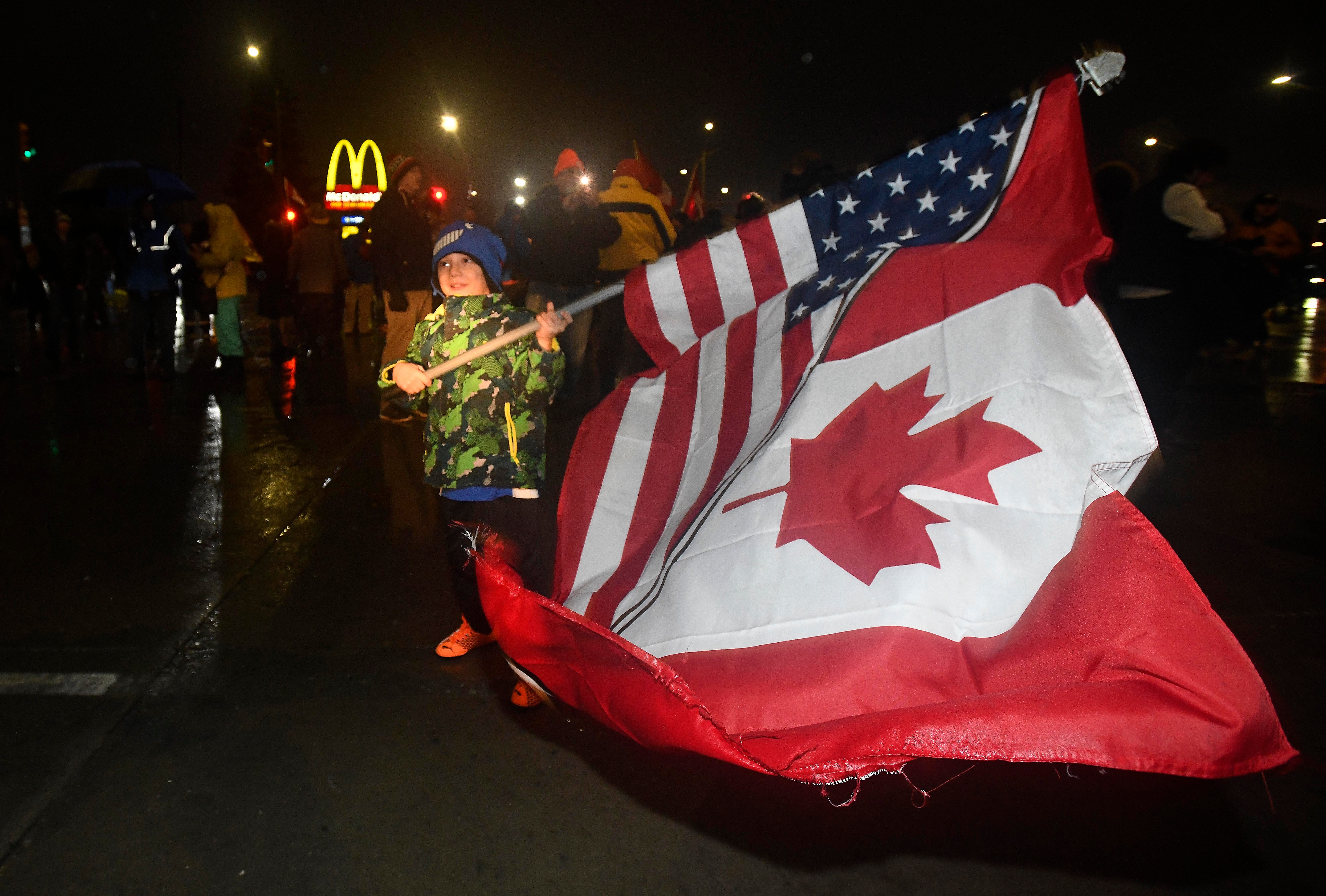 A young protester waves a half Canadian/half American flag in the street in Windsor, Canada on February 11, 2022 during a Canadian Freedom Convoy border blockade Friday night.