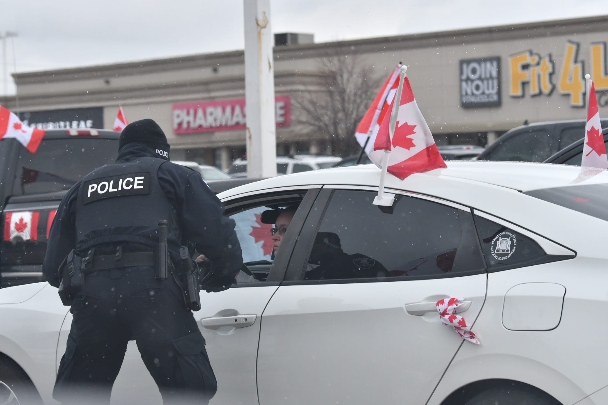 Windsor and London Police officers inform people parked in a shopping area parking lot on Huron Church Road that they cannot stay parked unless they are using the businesses and will be towed. This is not far from Ambassador Bridge in Windsor, Ontario, on Feb. 13, 2022.