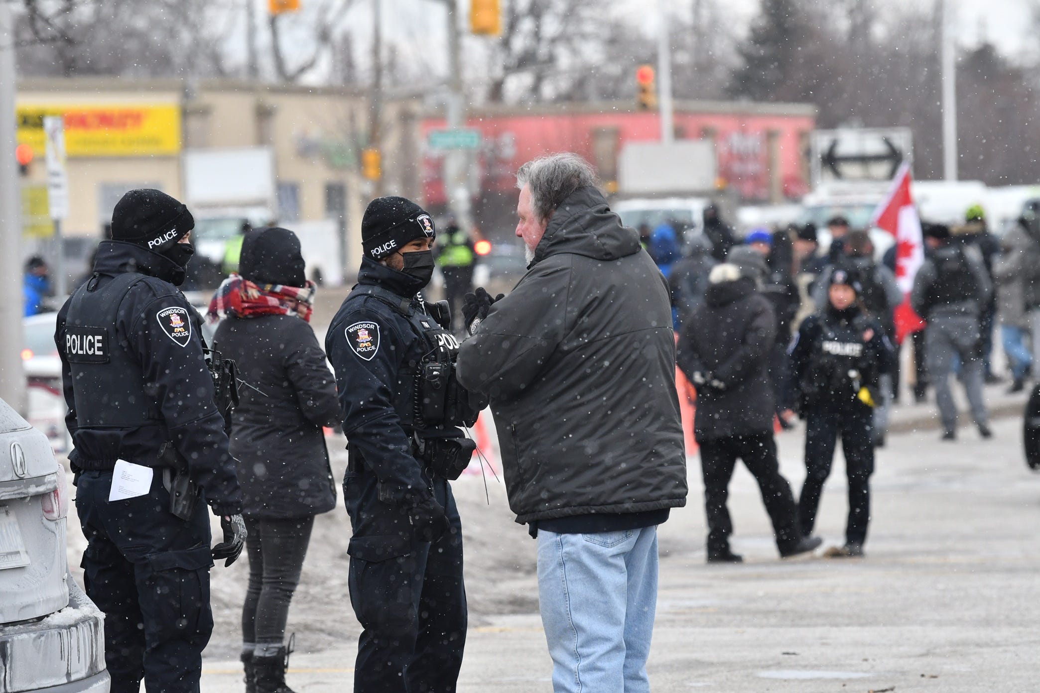 Windsor and London Police officers inform people parked in a lot on Huron Church Road that they cannot stay parked unless they are using the businesses and will be towed. This is not far from Ambassador Bridge in Windsor, Ontario, on Feb. 13, 2022.