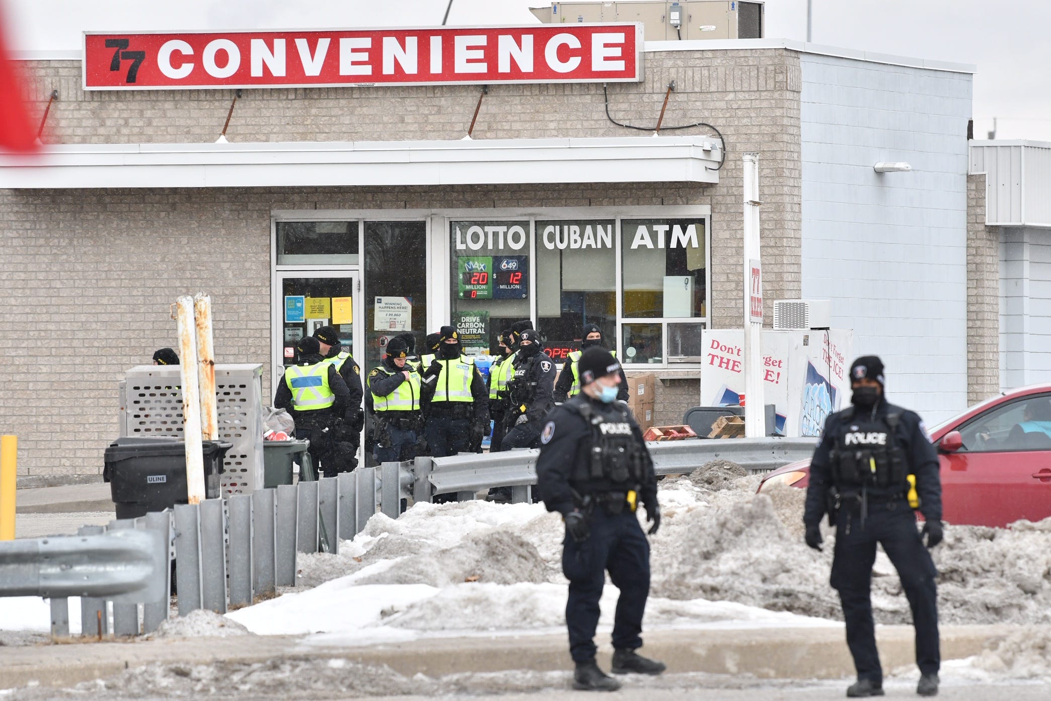 Windsor and London police officers inform people parked in a lot on Huron Church Road that they cannot stay parked unless they are using the businesses and will be towed. This is not far from Ambassador Bridge in Windsor, Ontario, on Feb. 13, 2022.
