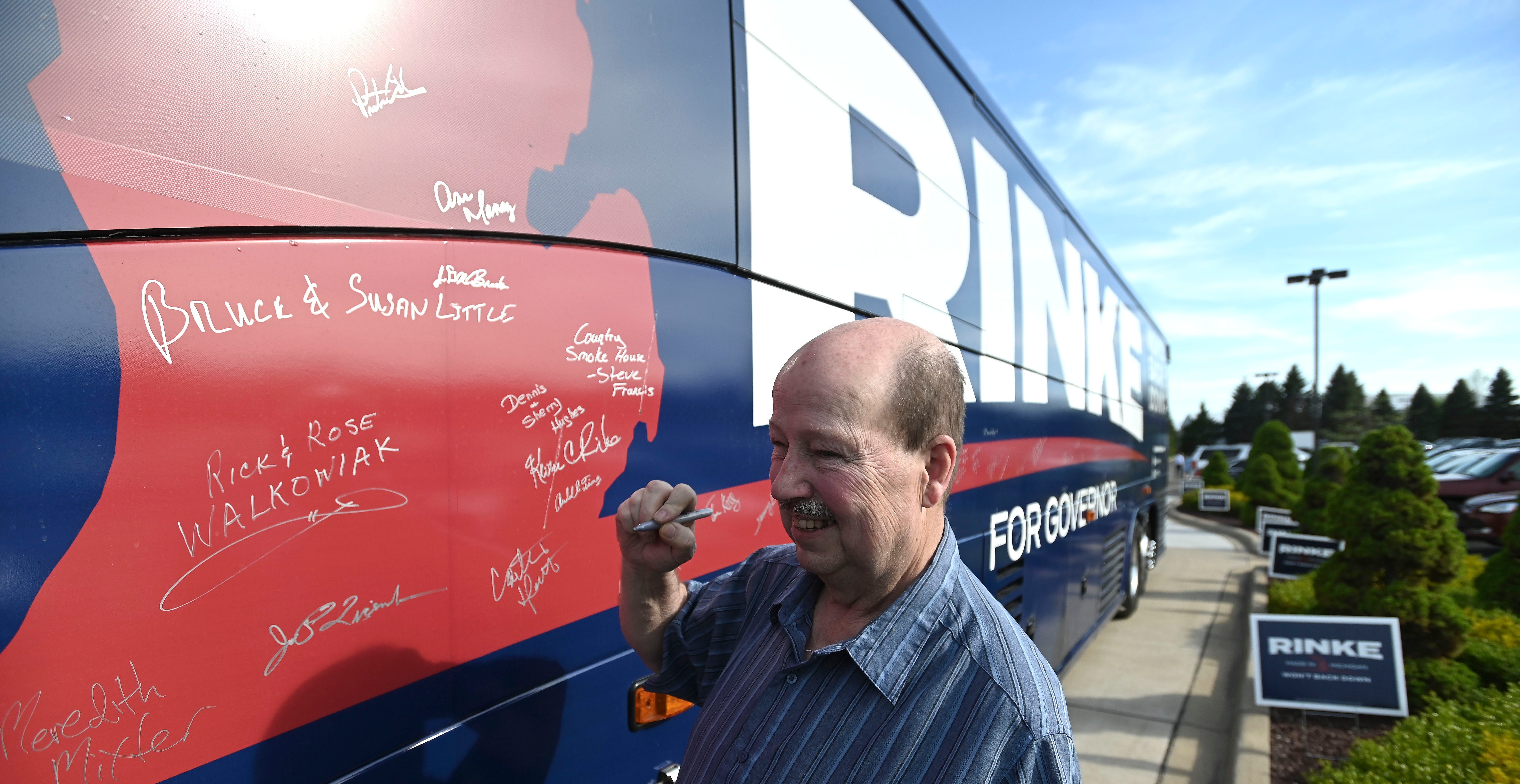 Bruce Little signs his name and the name of his wife, Susan, both of Williamston, on Candidate Kevin Rinke's bus, Thursday, May 12, 2022.  The Livingston County Republican Party's 2022 Lincoln Day Dinner features the First Official GOP Gubernatorial Debate at Crystal Gardens Event and Banquet Center in Howell, Thursday night, May 12, 2022.