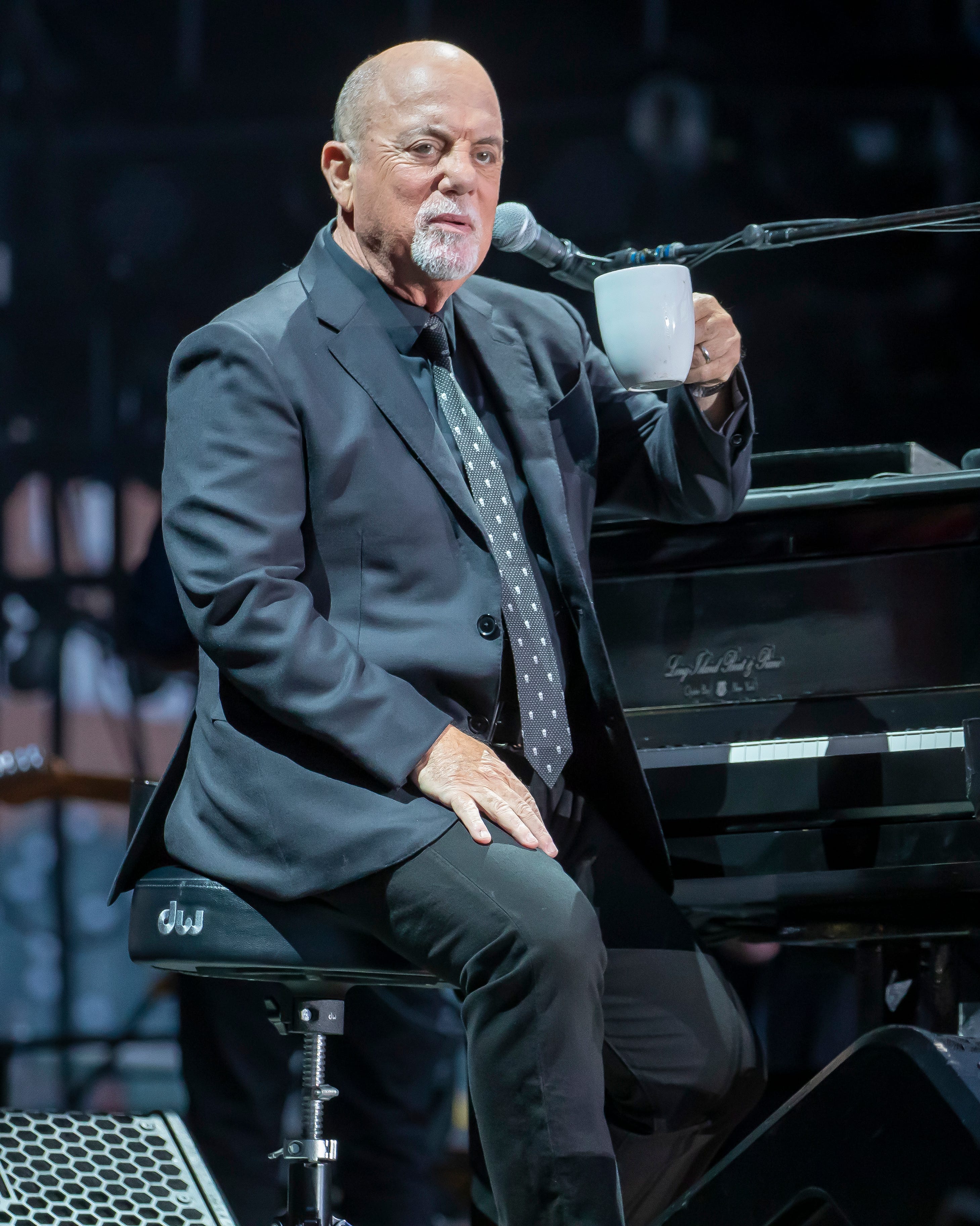 Billy Joel raises his coffee mug while performing in Detroit.