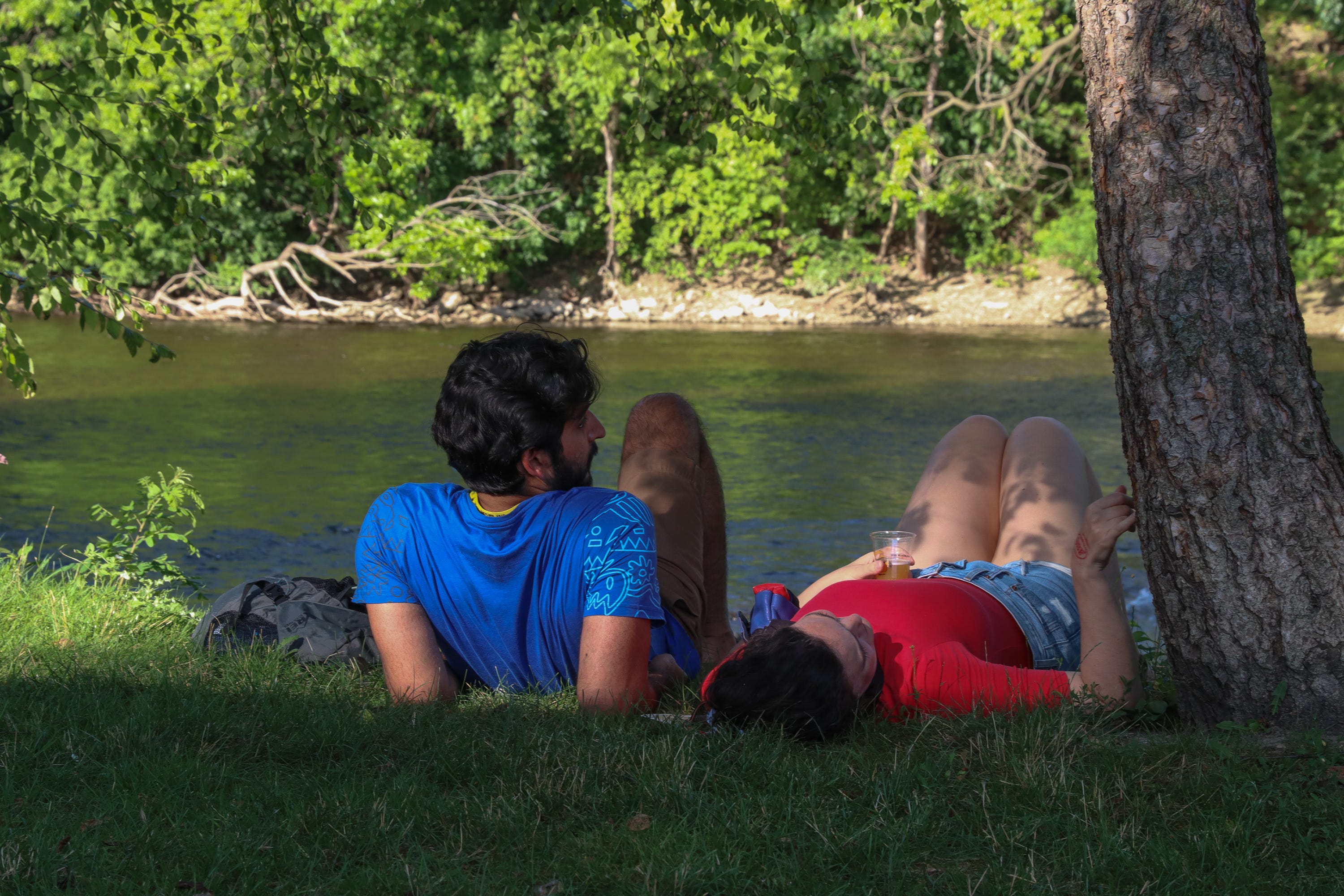 Priyank Kumal, left, and Sarra Rimer, right, both of Ypsilanti, relax along the Huron River at the Michigan Brewers Guild Summer Beer Festival on Friday, July 22, 2022.