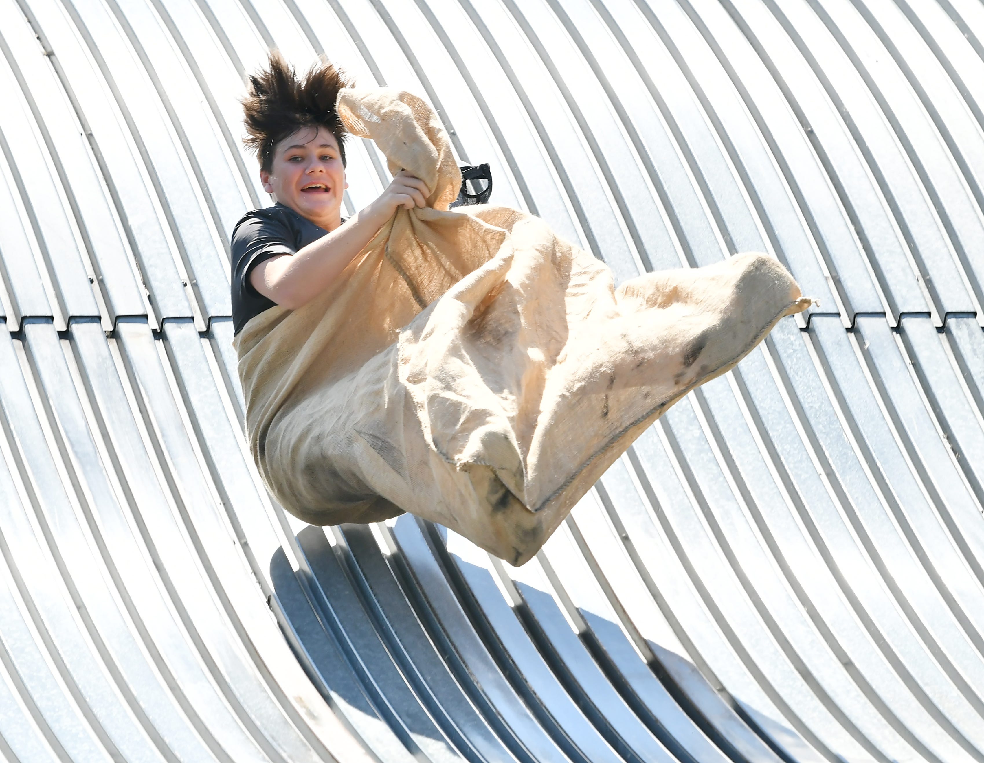 John Whitney, 12, of Royal Oak is airborne going down the giant slide on Belle Isle in Detroit on Aug. 19, 2022.