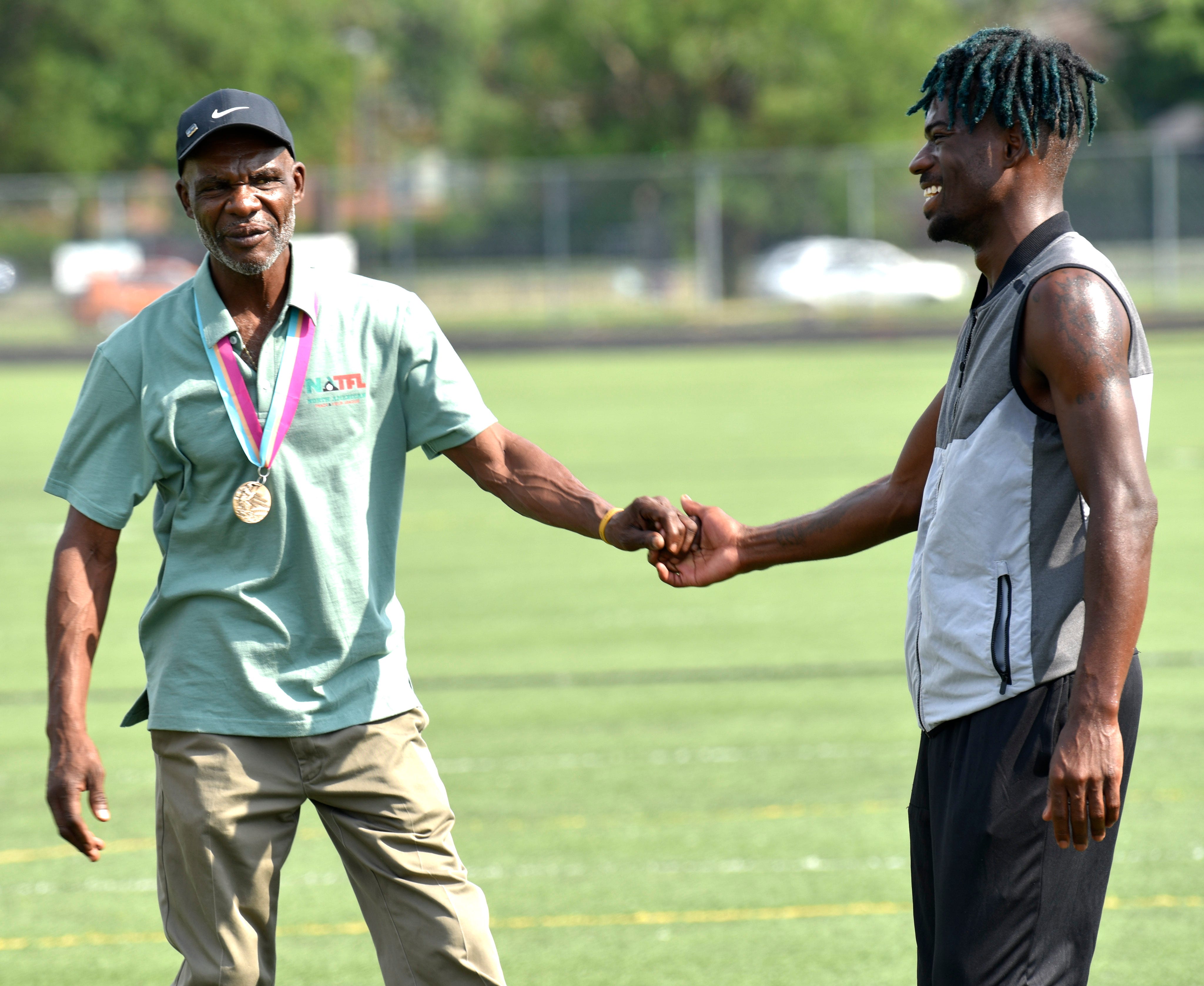 Earl Jones, left, shakes hands with runner Montel Lewis, 21, of Detroit, Saturday morning, Aug. 20, 2022. Jones won a bronze medal in the 800-meter run in the 1984 Olympics.