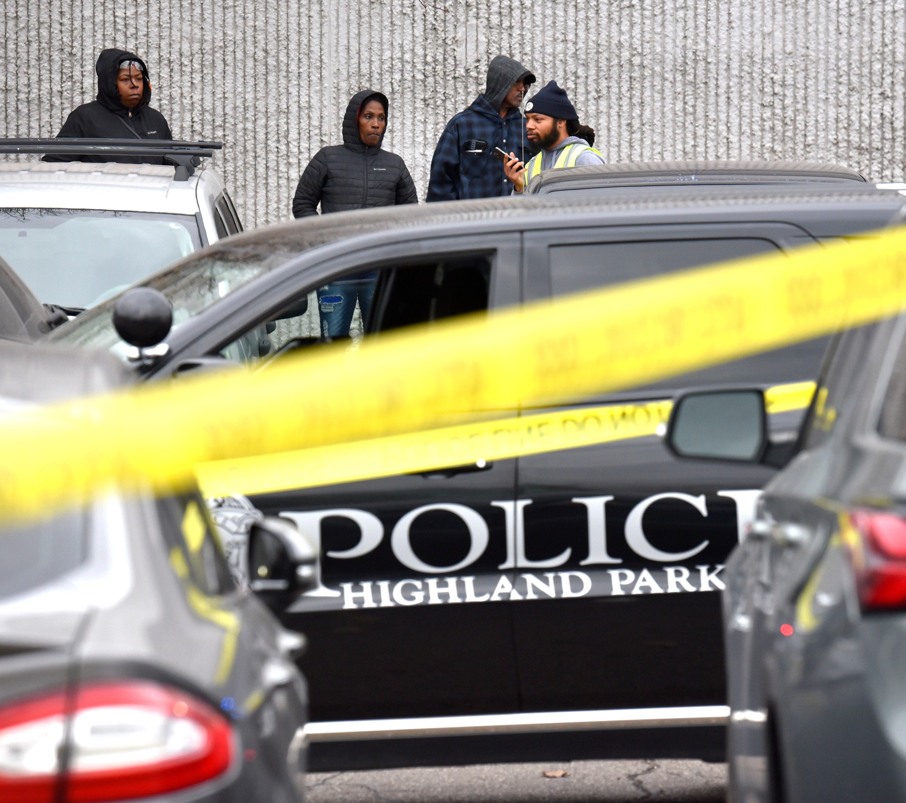 People stand outside the Faurecia plant in Highland Park as police investigate a deadly shooting in the front parking lot, Wednesday afternoon, December 14, 2022.