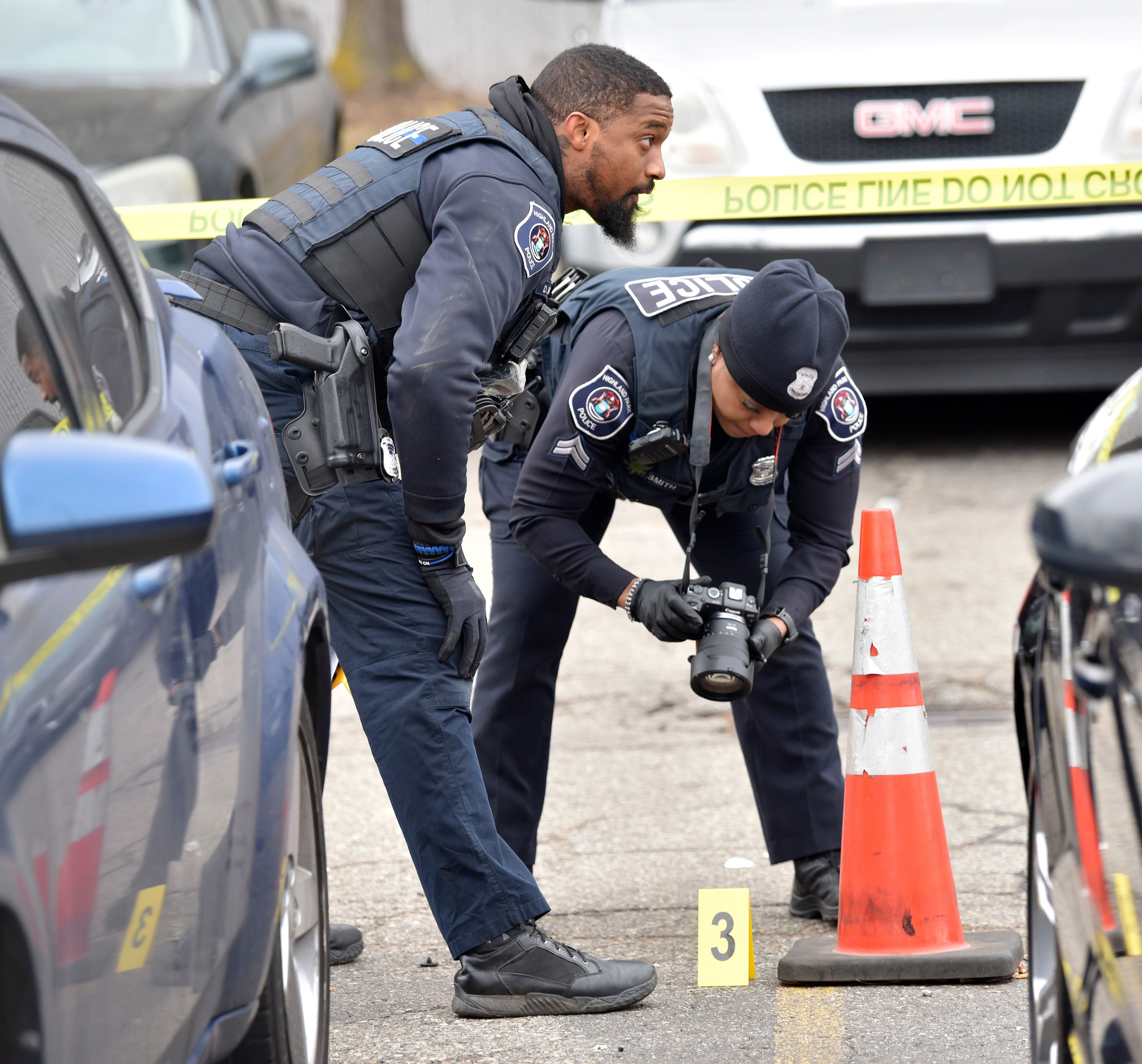 Police officers take pictures of a shell casing and evidence markers in the front parking lot of the Faurecia plant in Highland Park, Wednesday afternoon, December 14, 2022.
